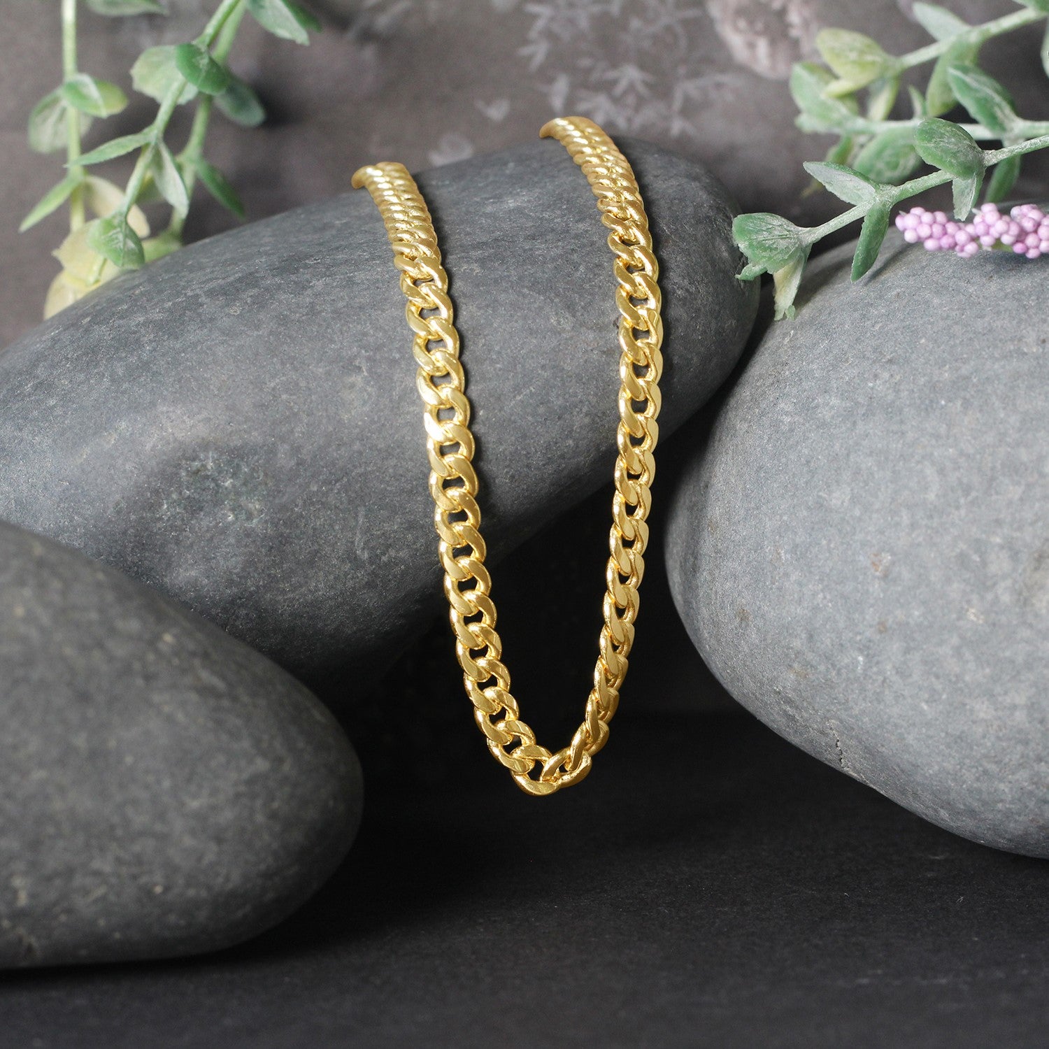 10k yellow gold Miami Cuban semi-solid chain, 4.5mm wide, draped over dark stones.