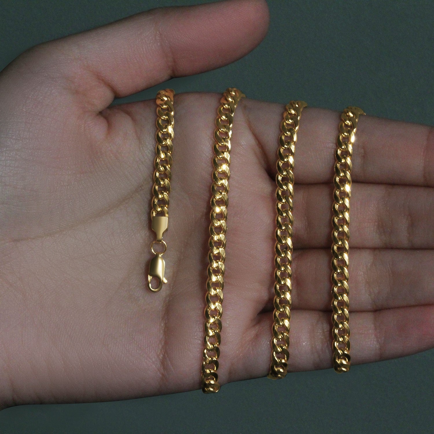 A 10k yellow gold Miami Cuban semi-solid chain with a lobster clasp is held in a hand.