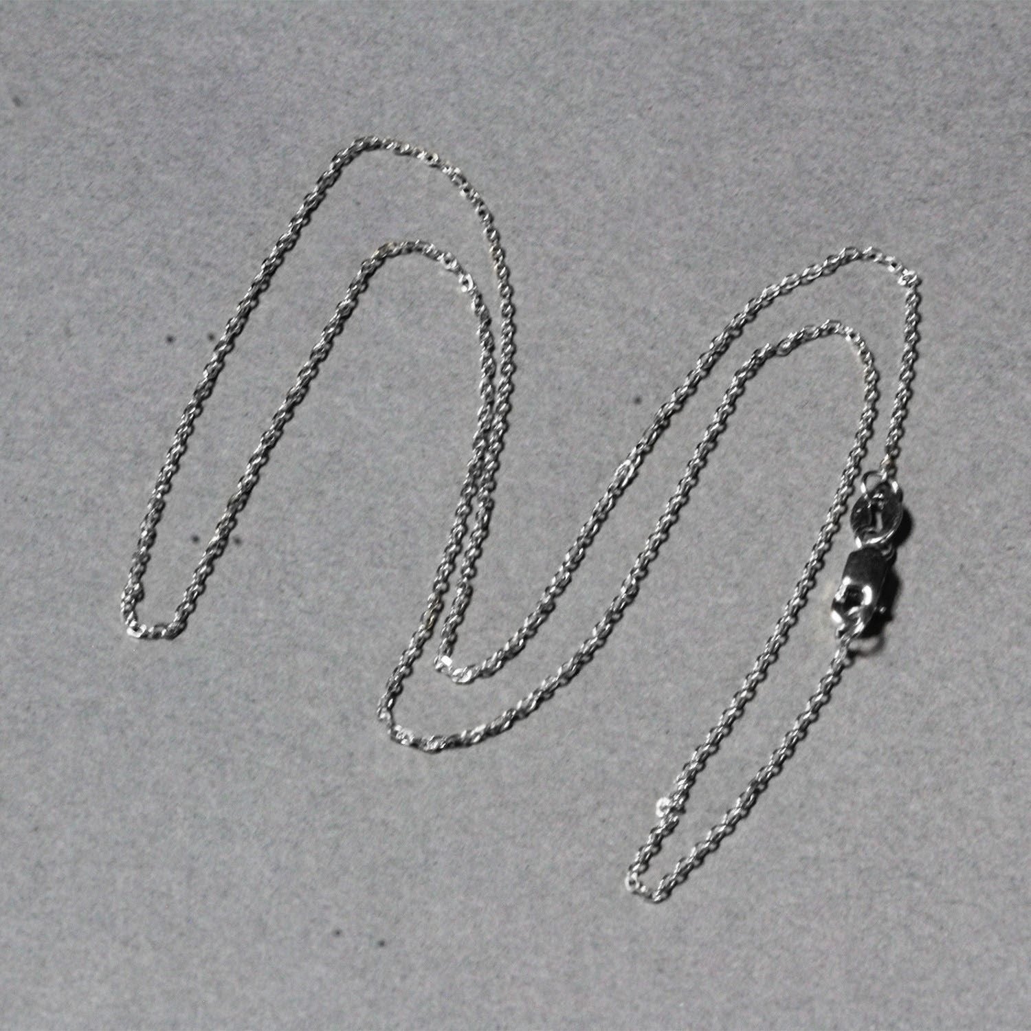 18k white gold diamond cut cable link chain with a lobster clasp on a gray background.