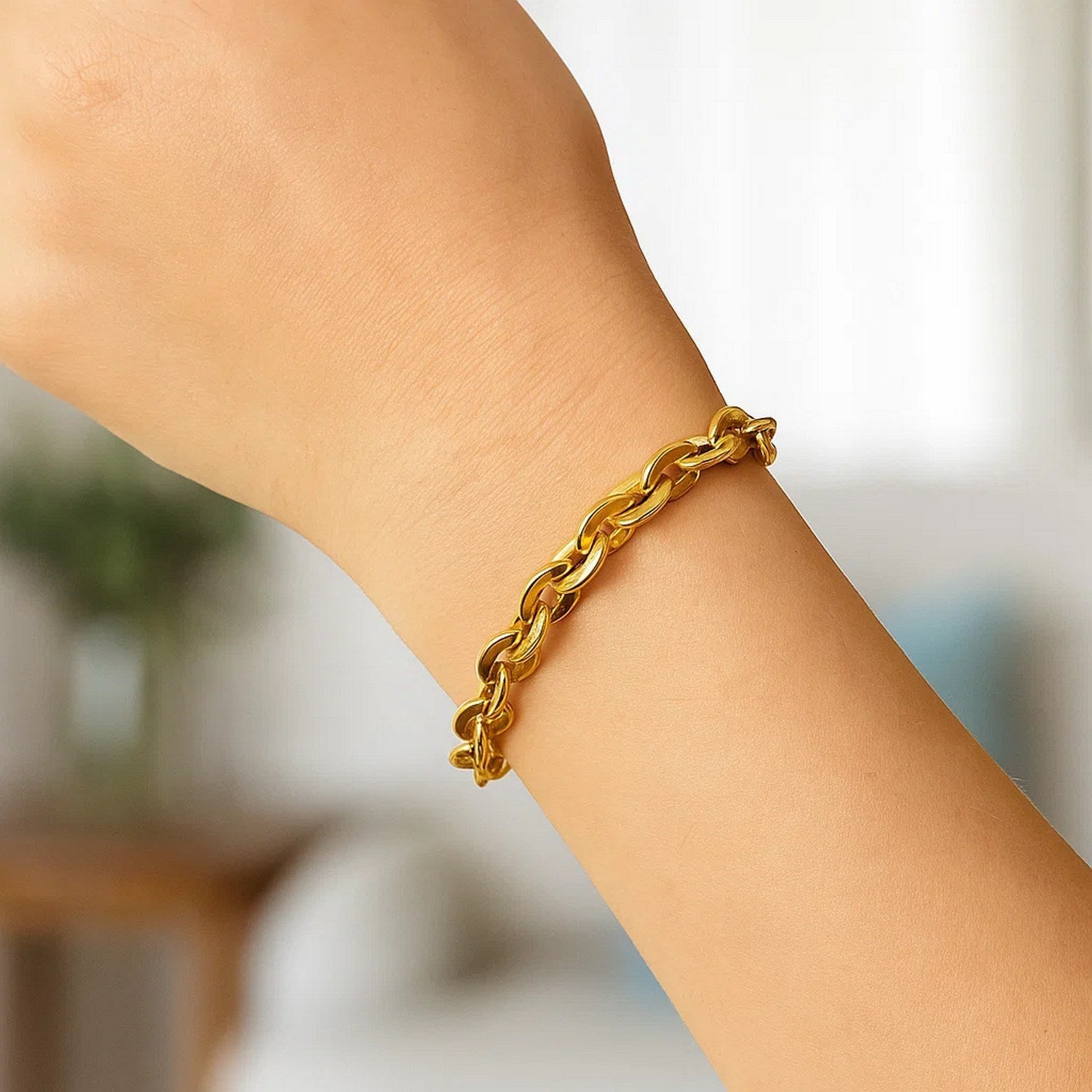 A 14K yellow gold mirror rolo link chain bracelet is worn on a wrist.