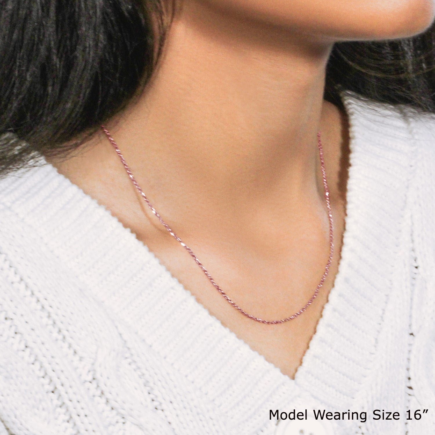 An 18k rose gold diamond cut cable link chain is worn around a model's neck.