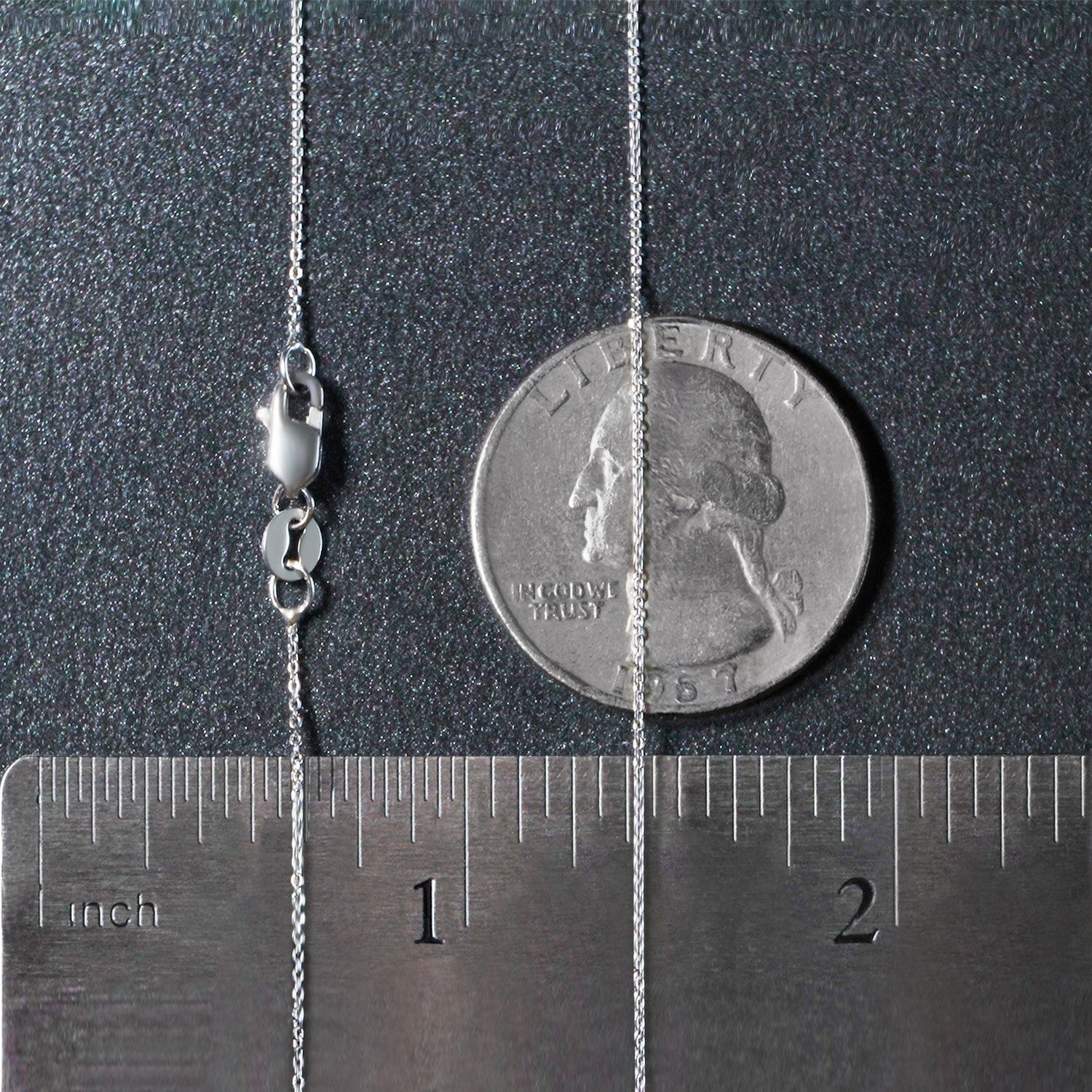 A 14k white gold cable link chain with a lobster clasp, measured against a ruler and coin.