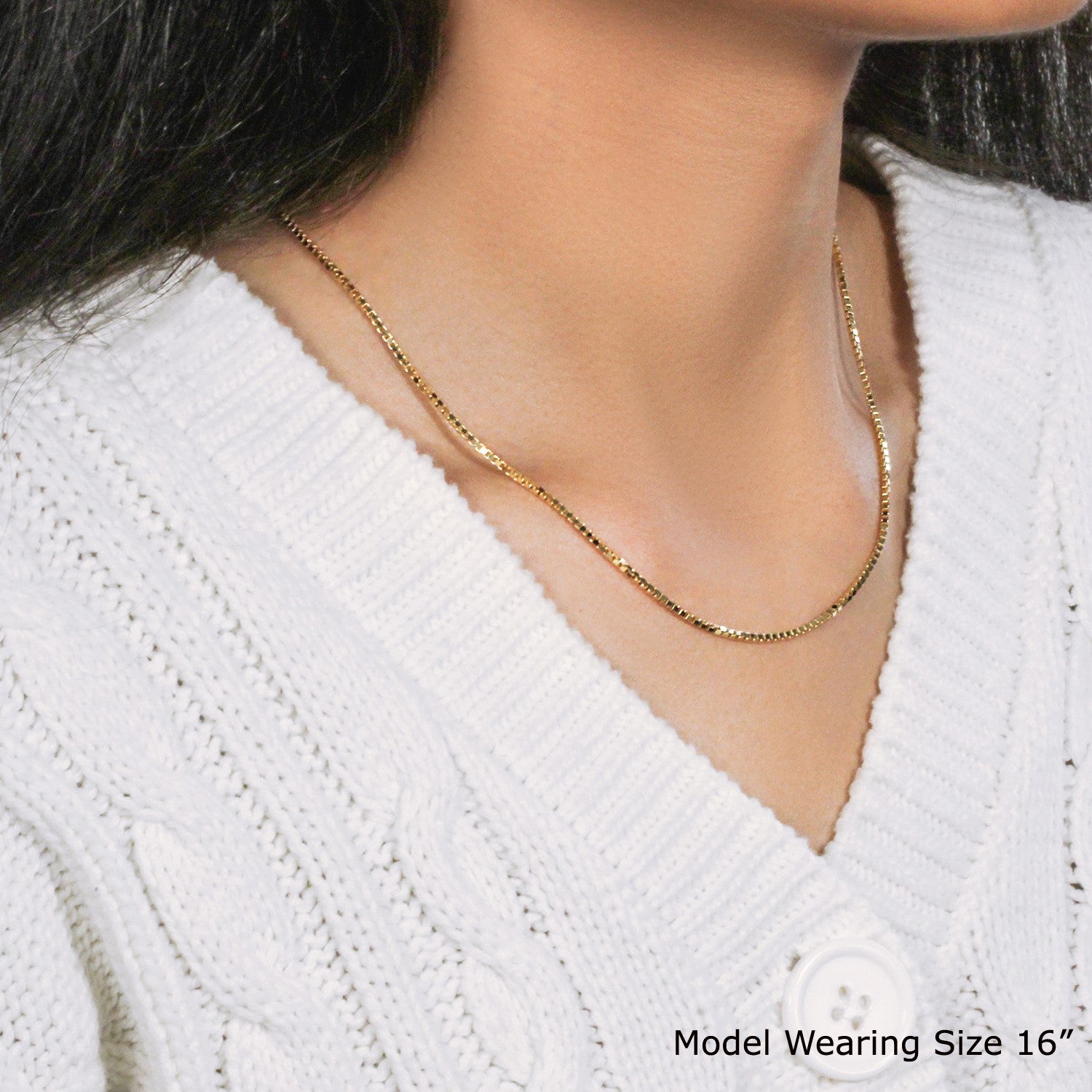 A 10k yellow gold classic box chain is worn around a model's neck over a white sweater.