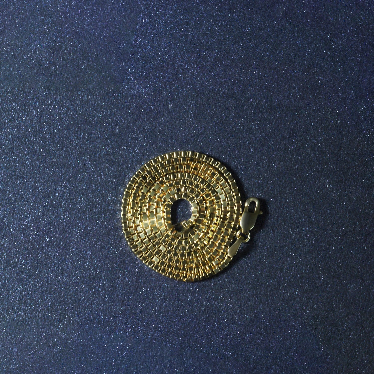 10k yellow gold classic box chain with a lobster clasp, coiled on a dark surface.