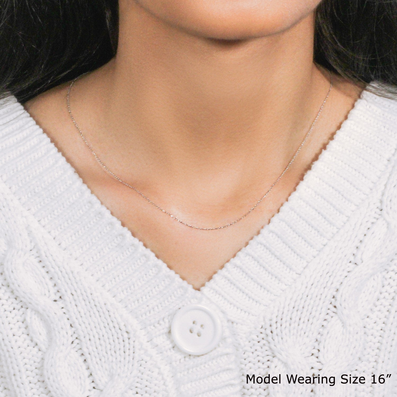 A thin 14k white gold diamond cut cable link chain is worn around a person's neck.