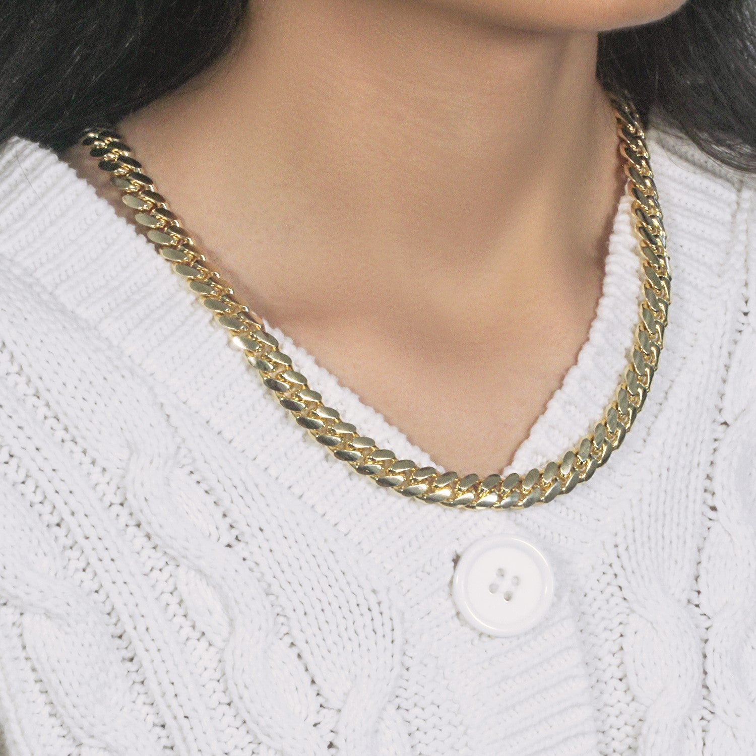 14k yellow gold classic Miami Cuban solid chain on a person wearing a white cable-knit sweater.