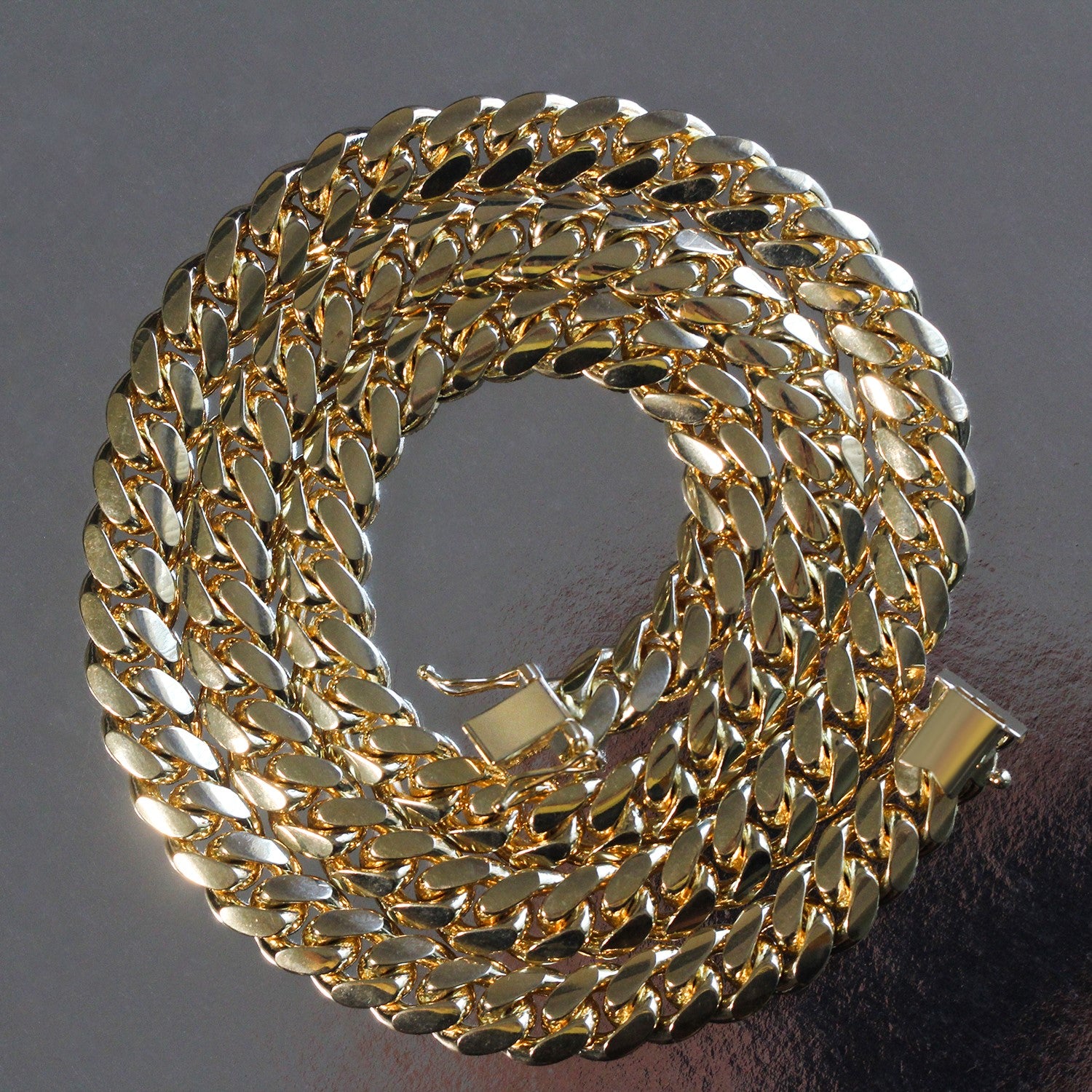 14k yellow gold classic Miami Cuban solid chain, 9.20 mm wide, coiled on a dark surface.