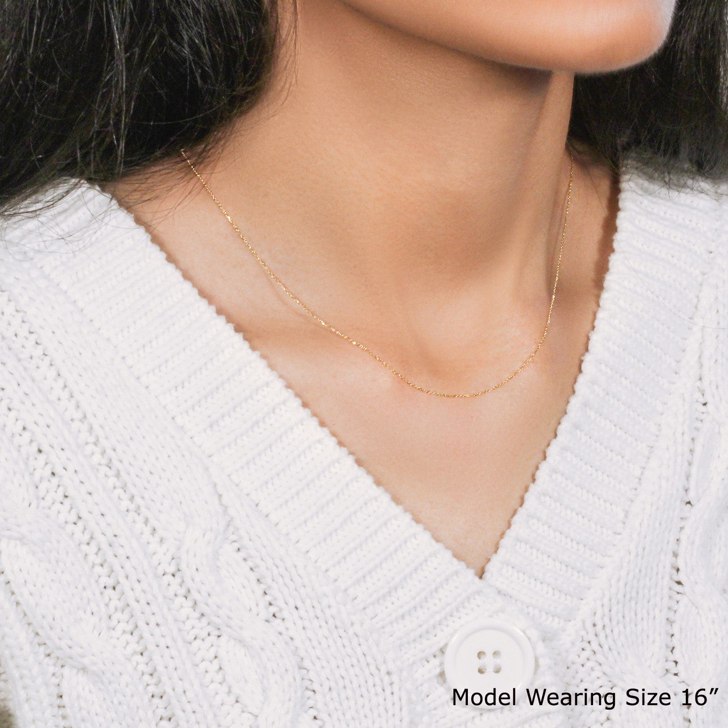 A 14k yellow gold diamond-cut cable link chain is worn around a person's neck.