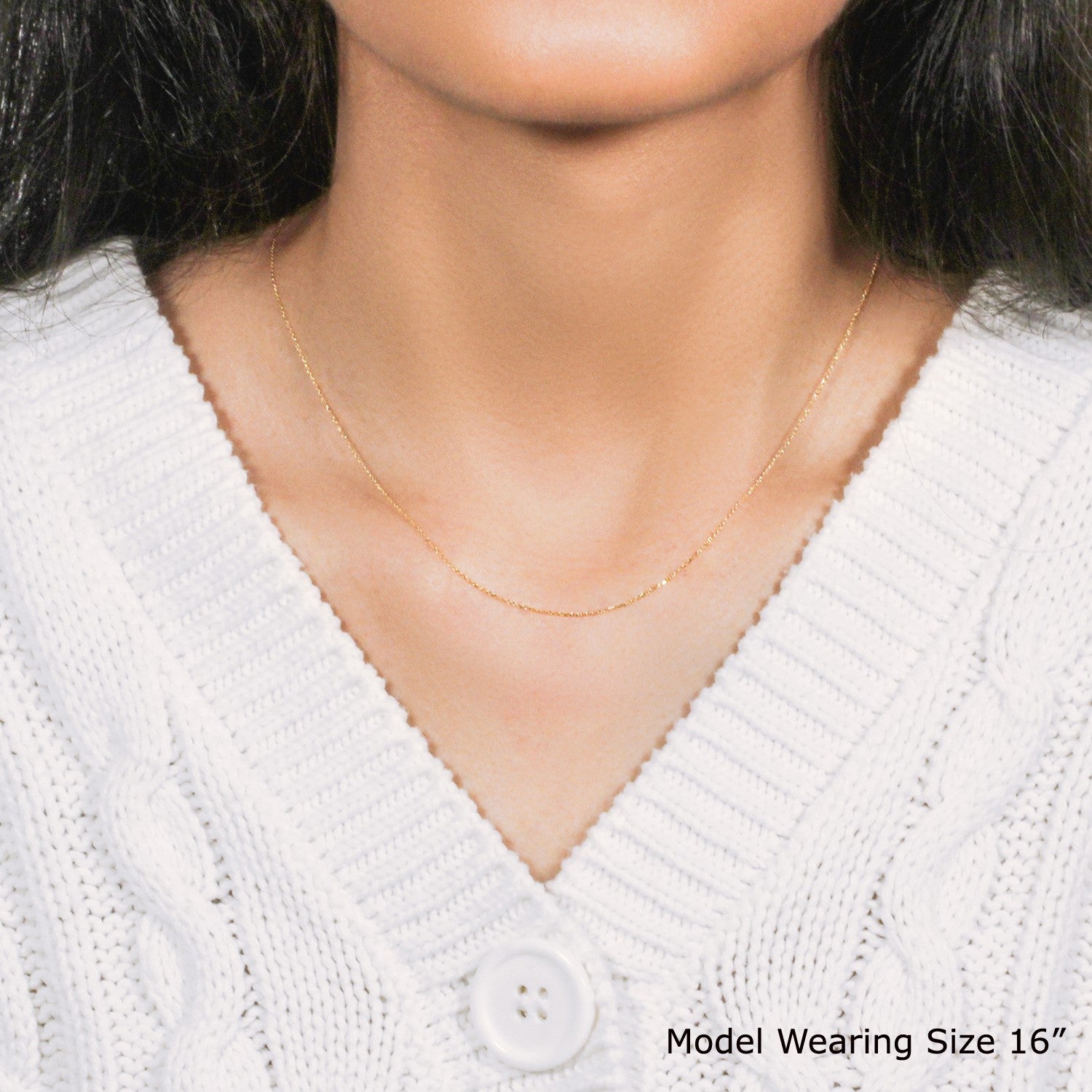 A 14k yellow gold diamond-cut cable link chain worn by a model.