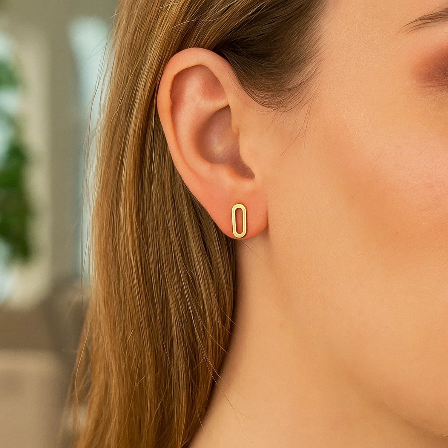 A woman wears a single 14k yellow gold paperclip link stud earring.