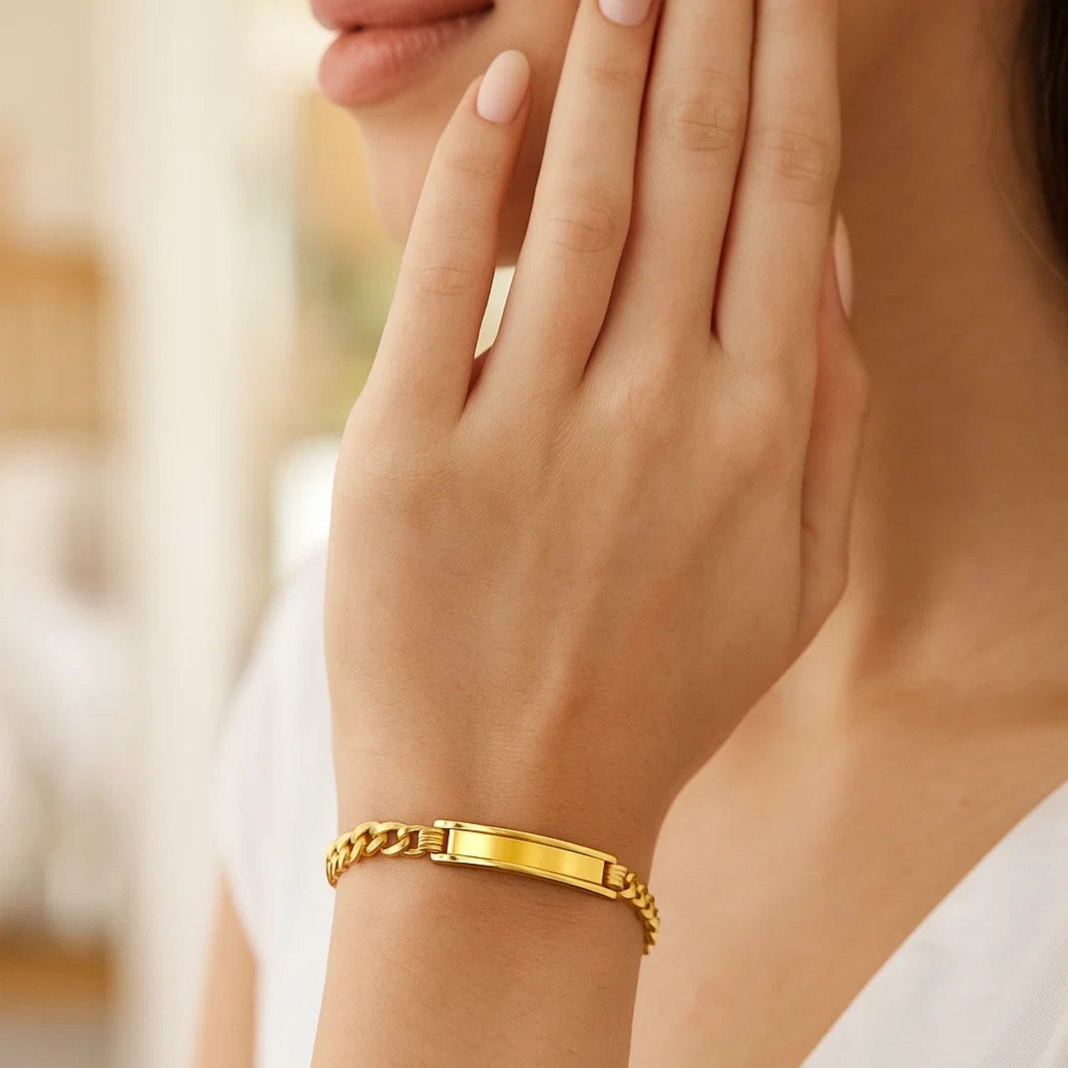 14k yellow gold curb ID bracelet with a polished rectangular plate on a woman's wrist.