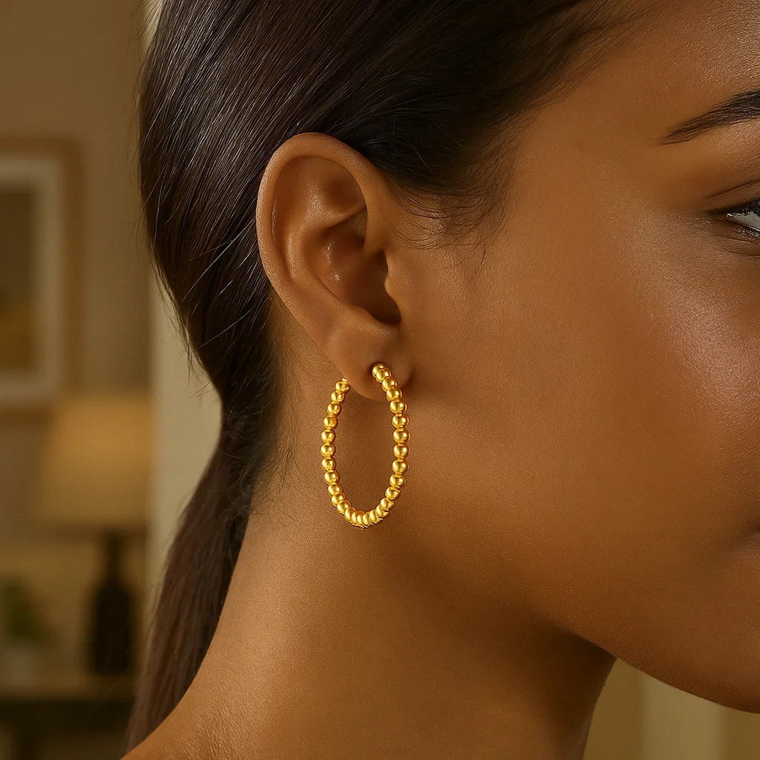 14K yellow gold polished large bead hoop earrings on a woman's ear.