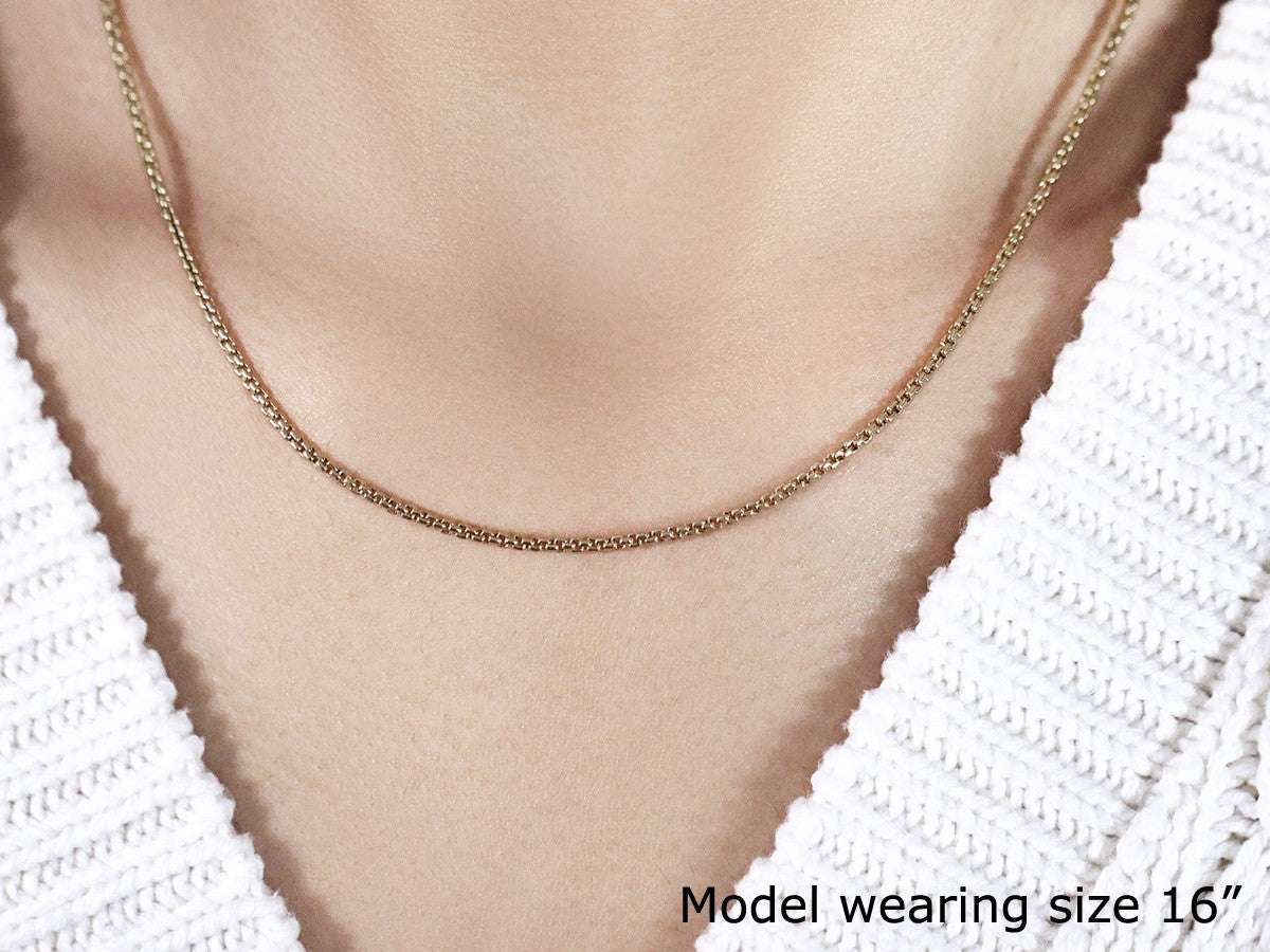 A 14k yellow gold solid round box chain, 1.6mm wide, worn by a model.