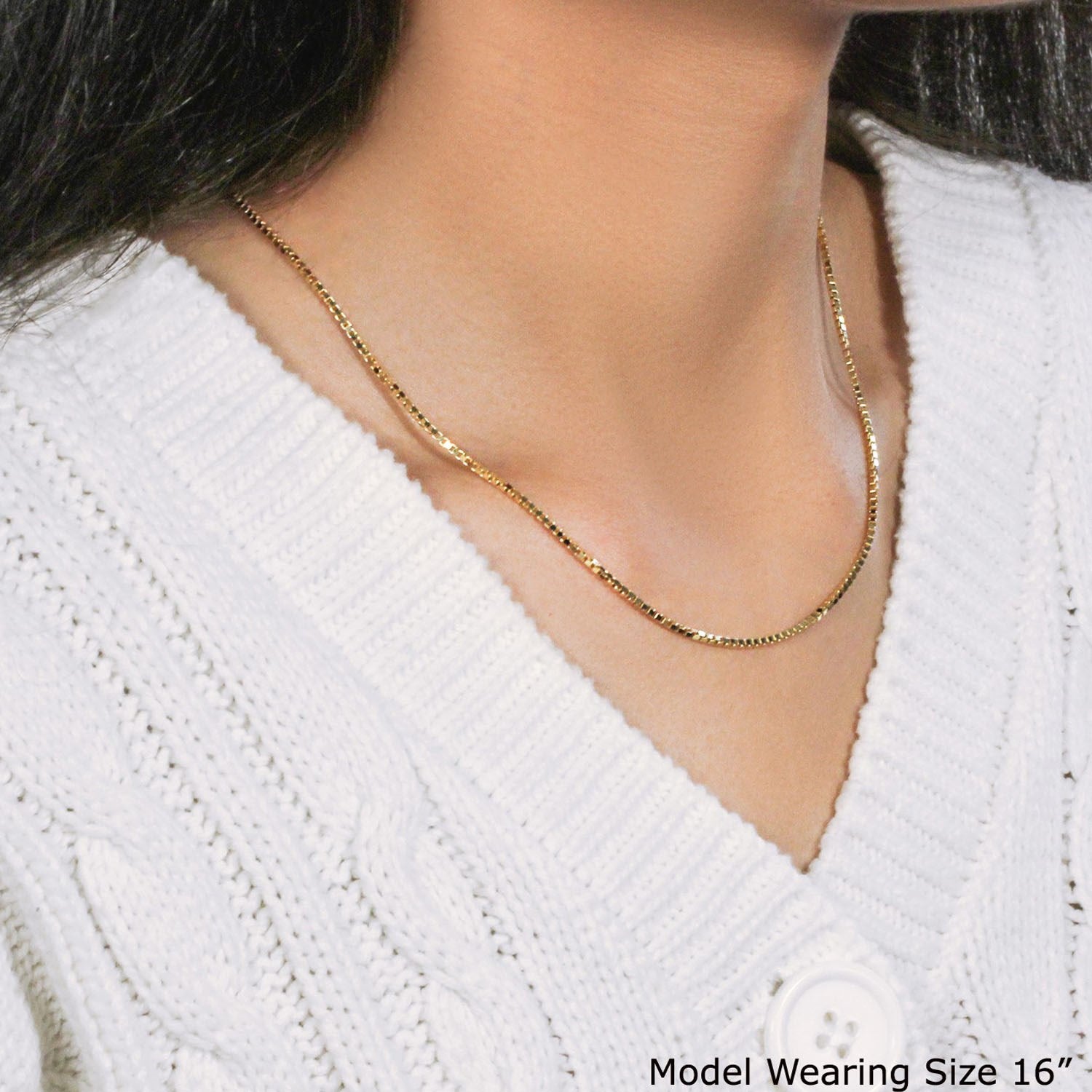 A 14K yellow gold classic box chain is worn around a model's neck over a white sweater.