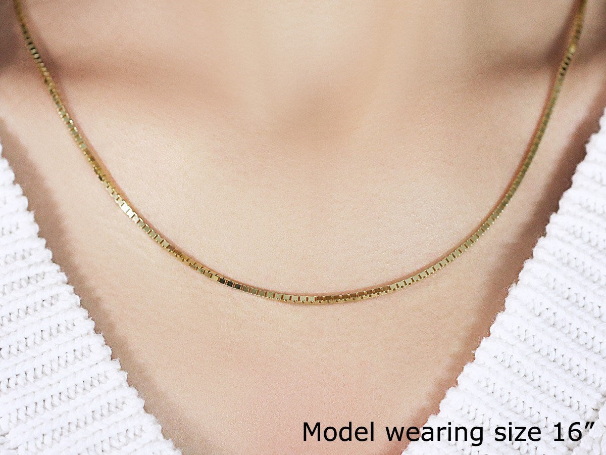 A 14K yellow gold classic box chain, 1.7mm wide, worn by a model.