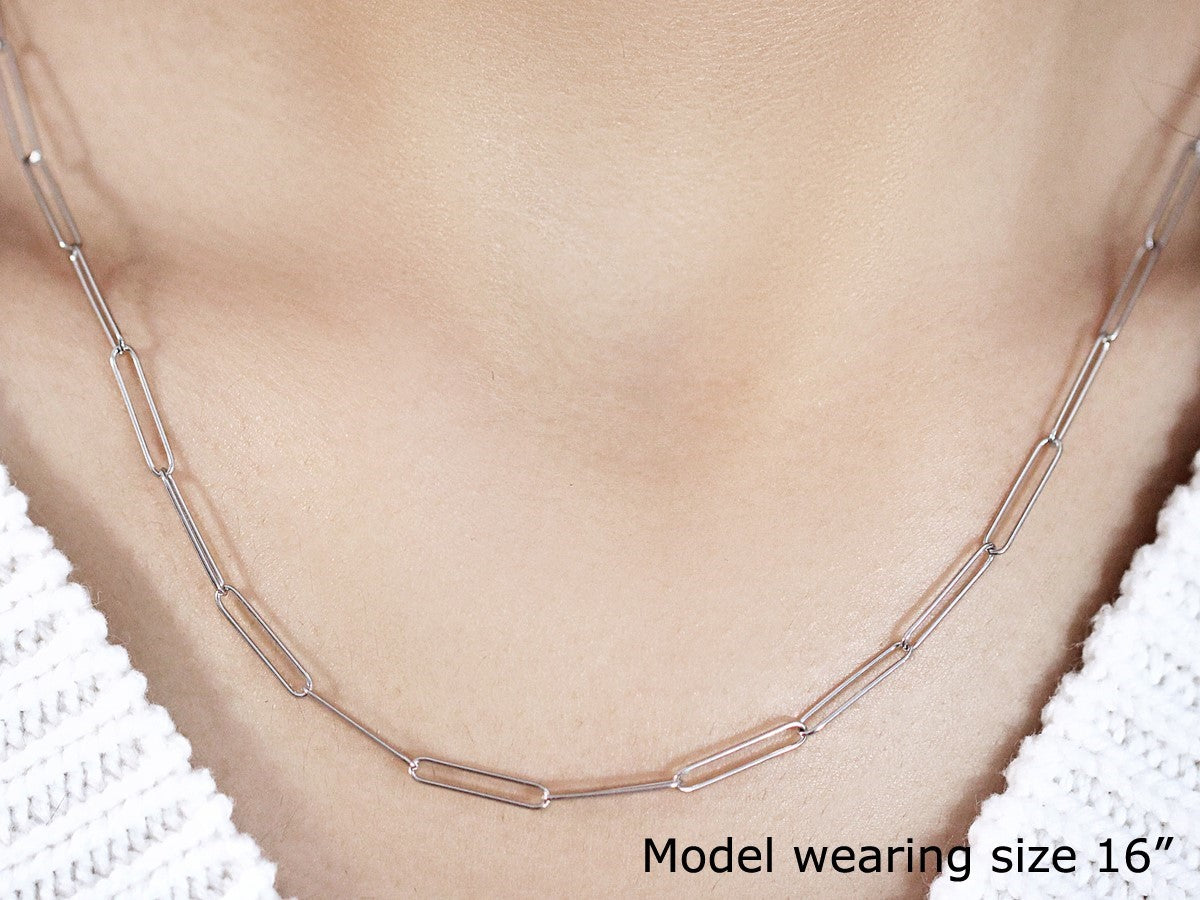 A 14k white gold paperclip chain with 2.7mm links is worn around a model's neck.