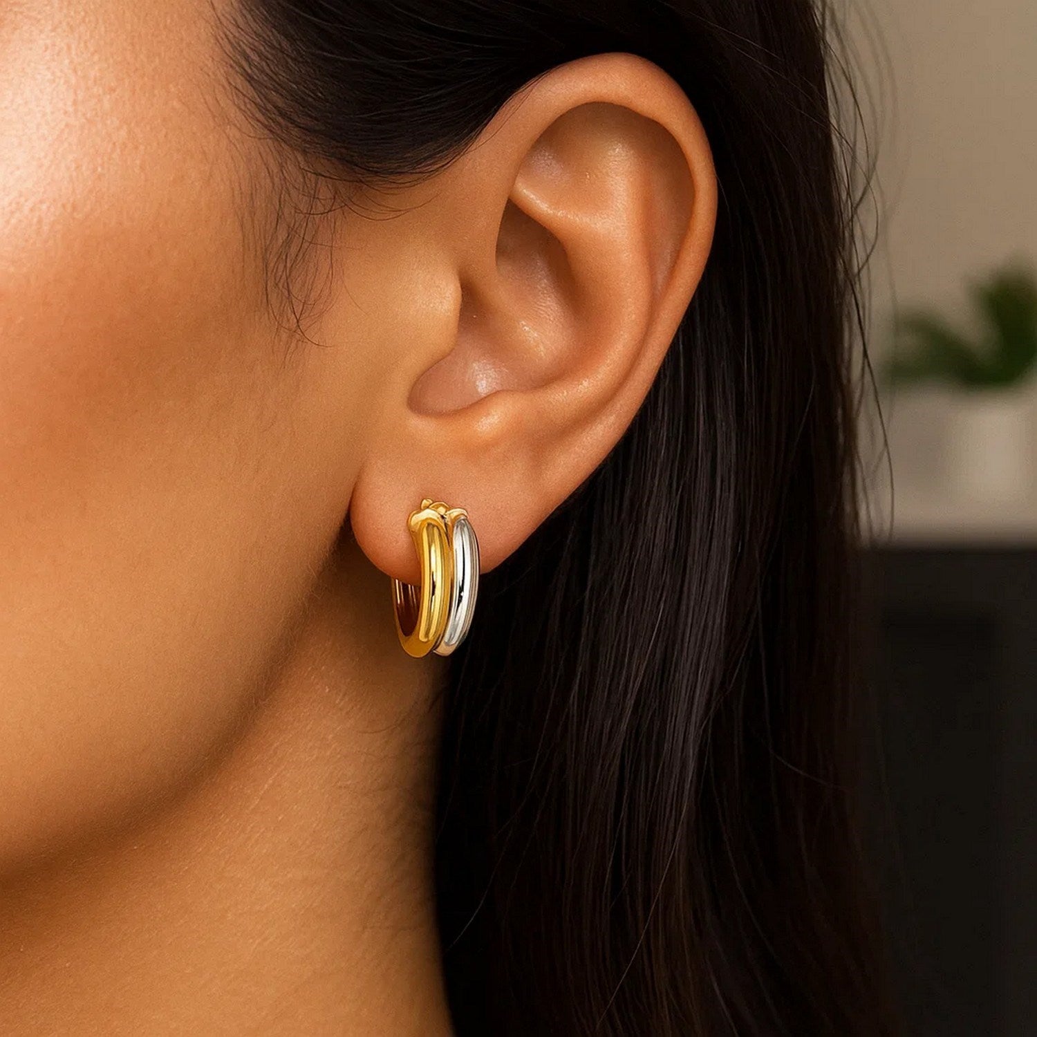A woman wears two-tone gold double round hoop earrings.