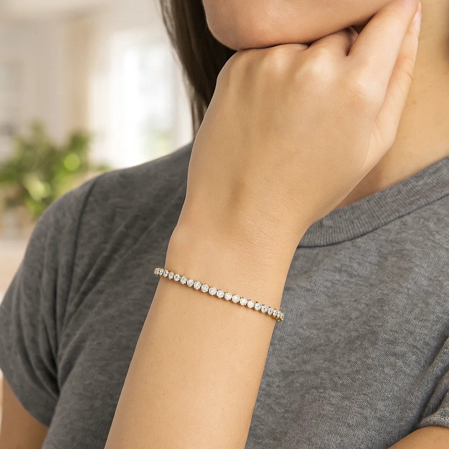 A 14K two-tone gold tennis bracelet with round diamonds on a woman's wrist.