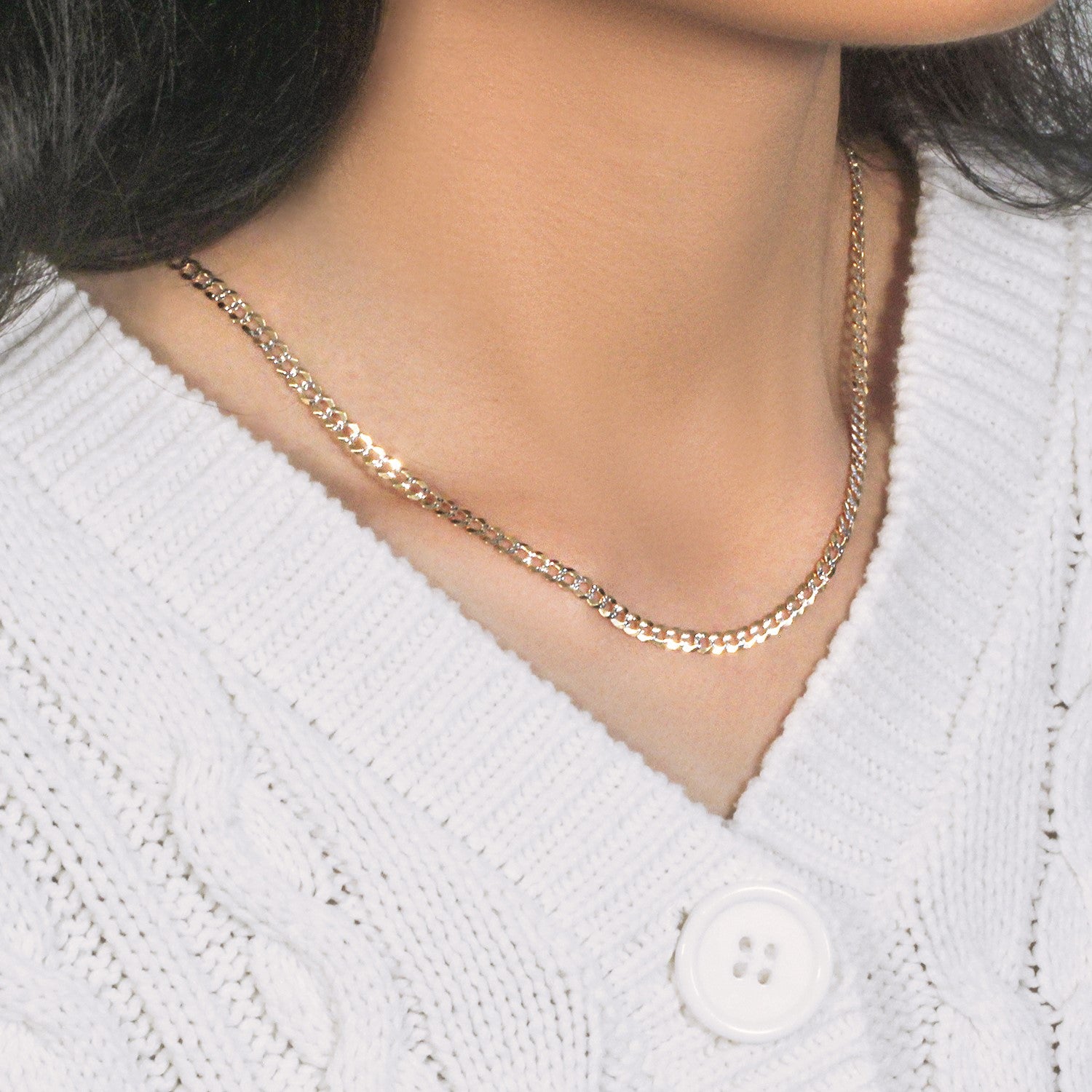 14k two-tone gold pave curb chain on a person wearing a white cable-knit sweater.