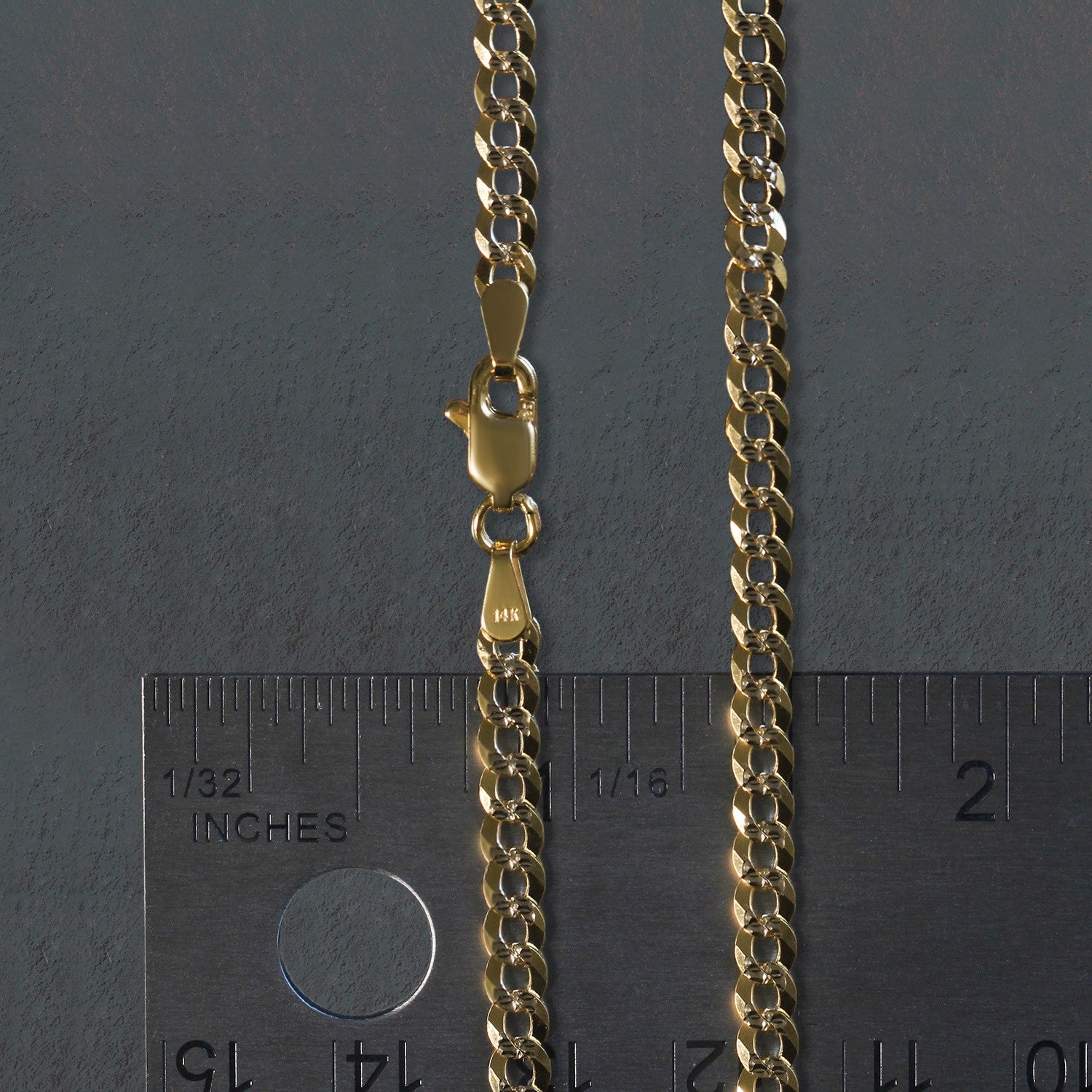 A 14k two-tone gold pave curb chain with a lobster clasp is shown next to a ruler.