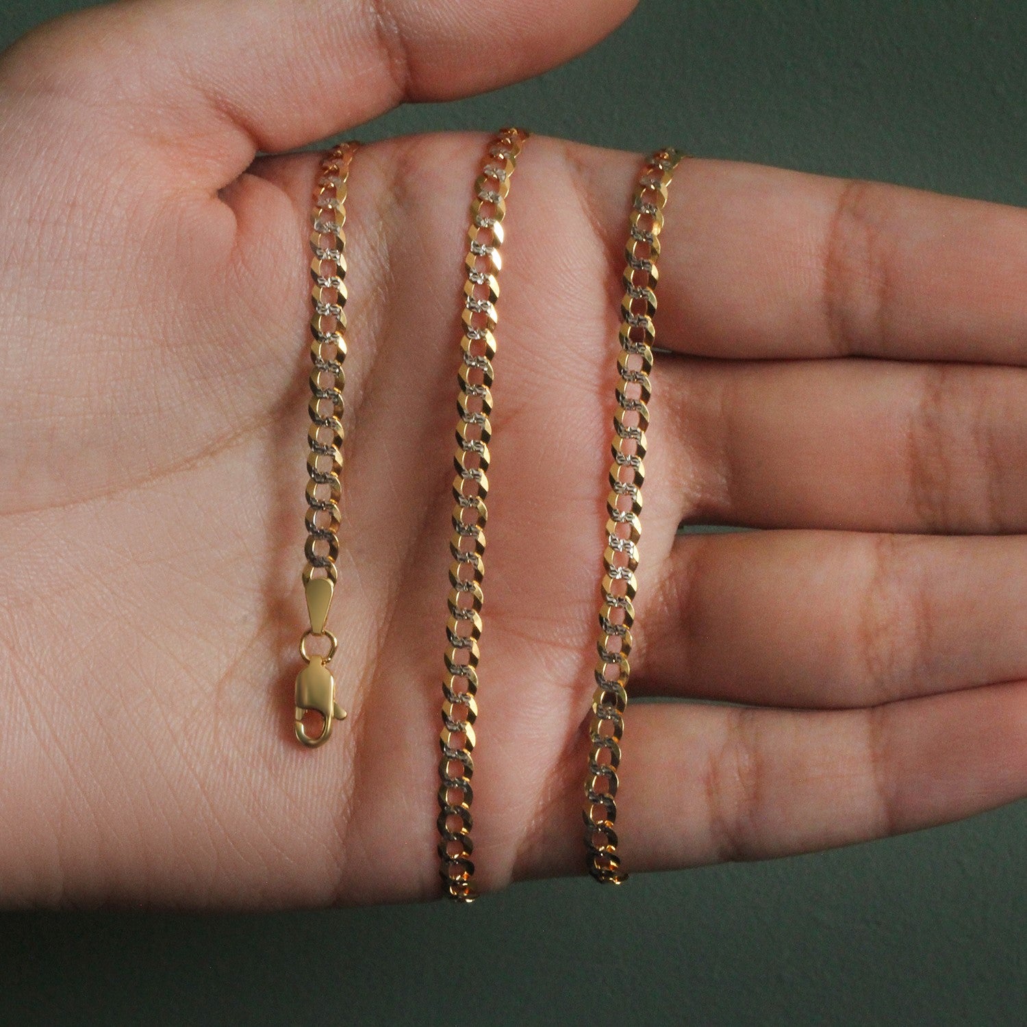 14k two-tone gold pave curb chain with a lobster clasp, held in an open hand.