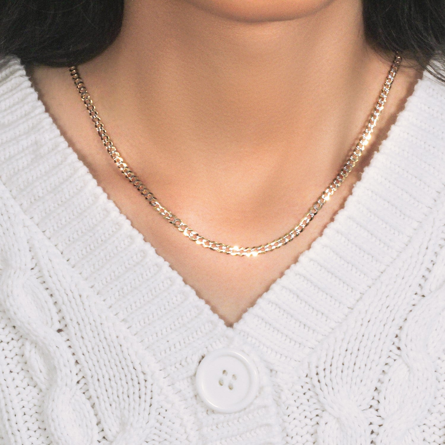 A 14k two-tone gold pave curb chain is worn around a person's neck.