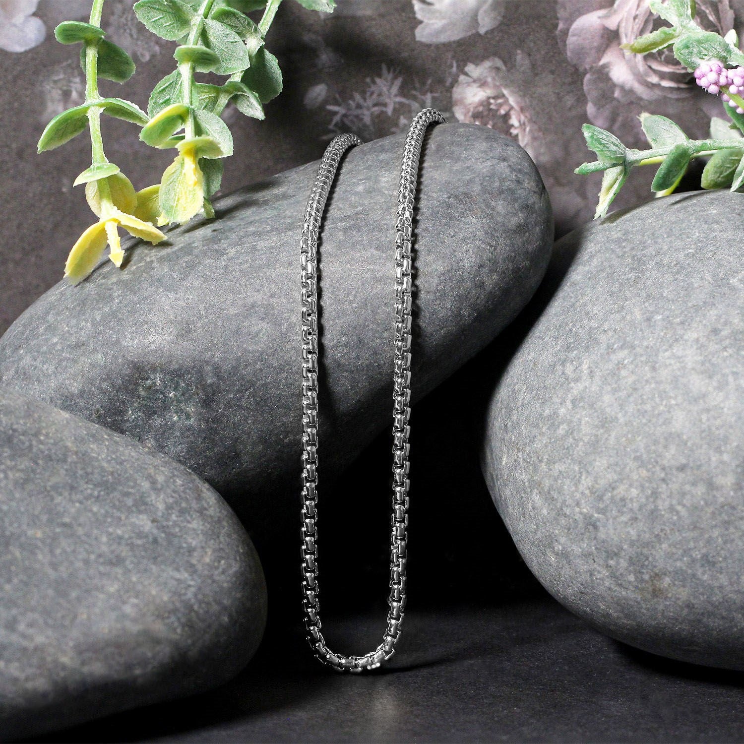 14k white gold solid round box chain (2.5 mm) draped over smooth gray stones.