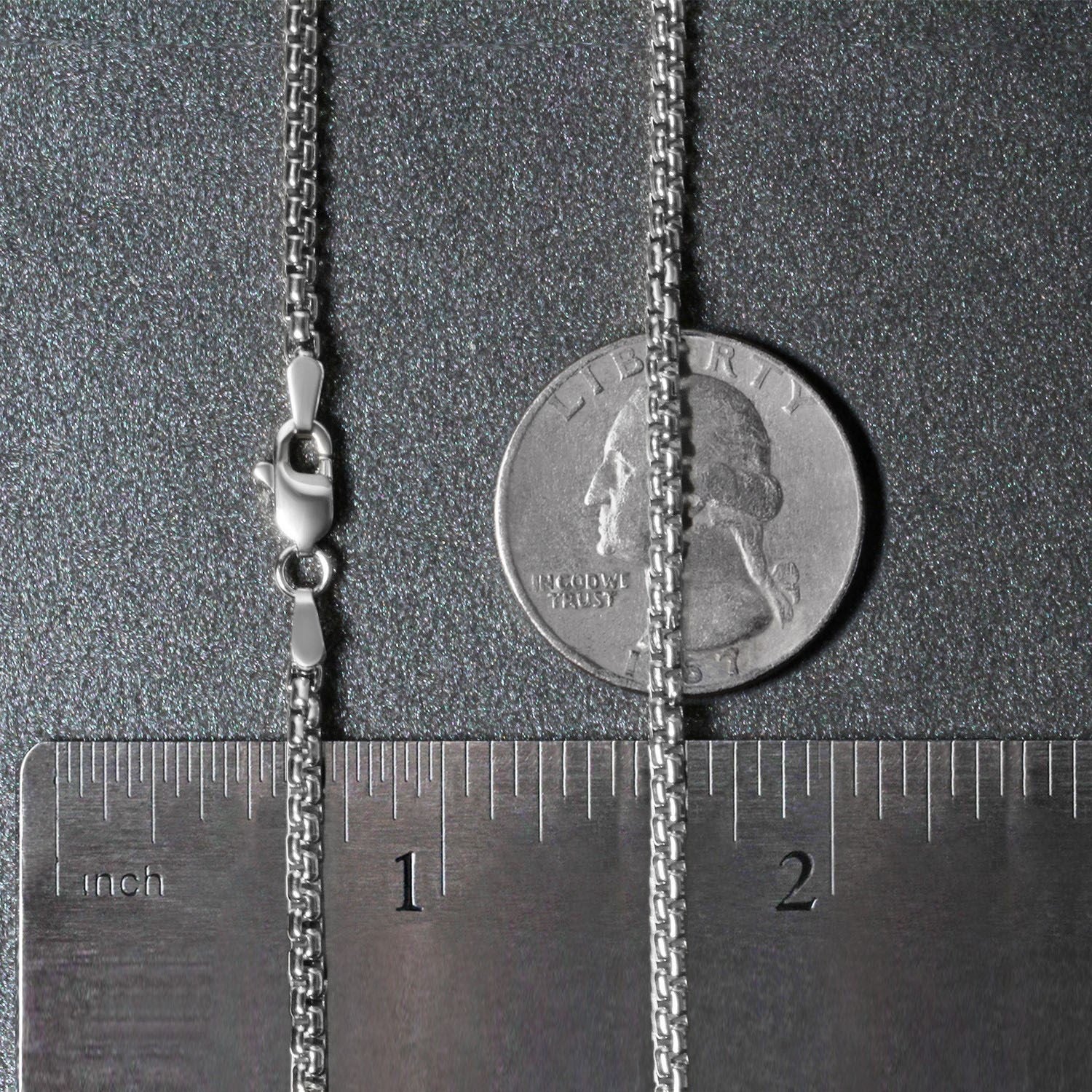 A 14k white gold solid round box chain with a lobster clasp, measured against a ruler and a quarter.