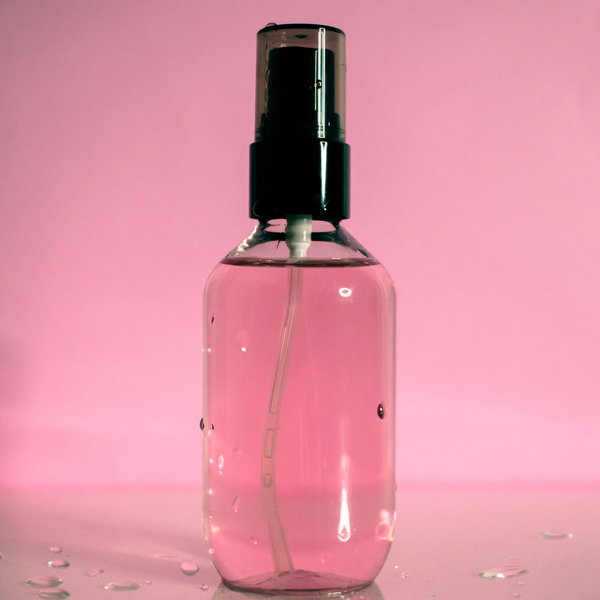 Pink oil control setting spray in a clear bottle with a black cap.