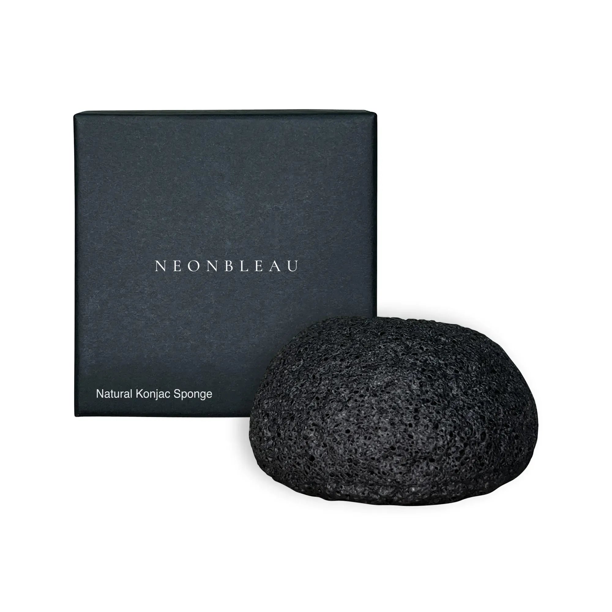 A black Konjac sponge sits next to its dark gray box.