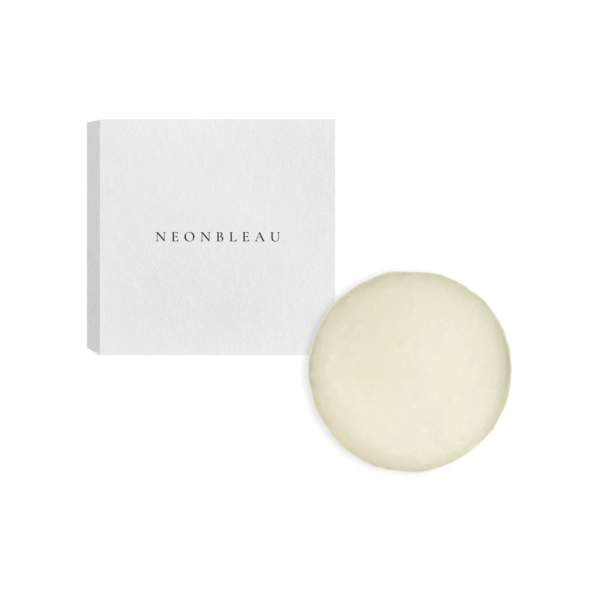 A white box with "NEONBLEAU" printed on it sits next to a round, light yellow conditioner bar.