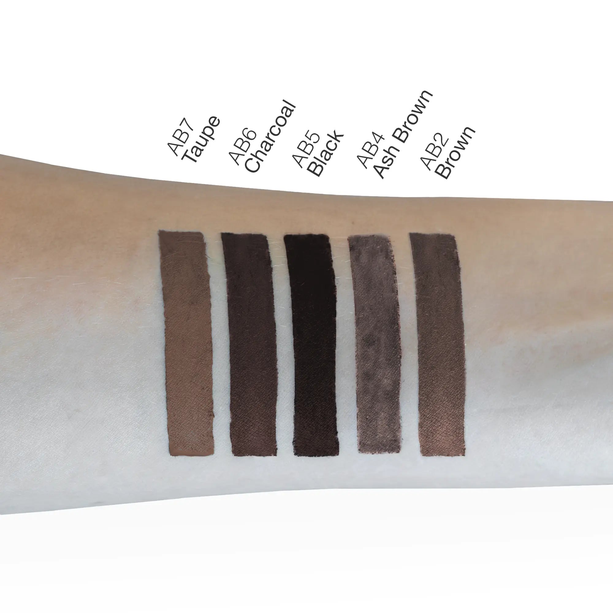 Six eyebrow pencil swatches in shades of brown, charcoal, and black are shown on an arm.