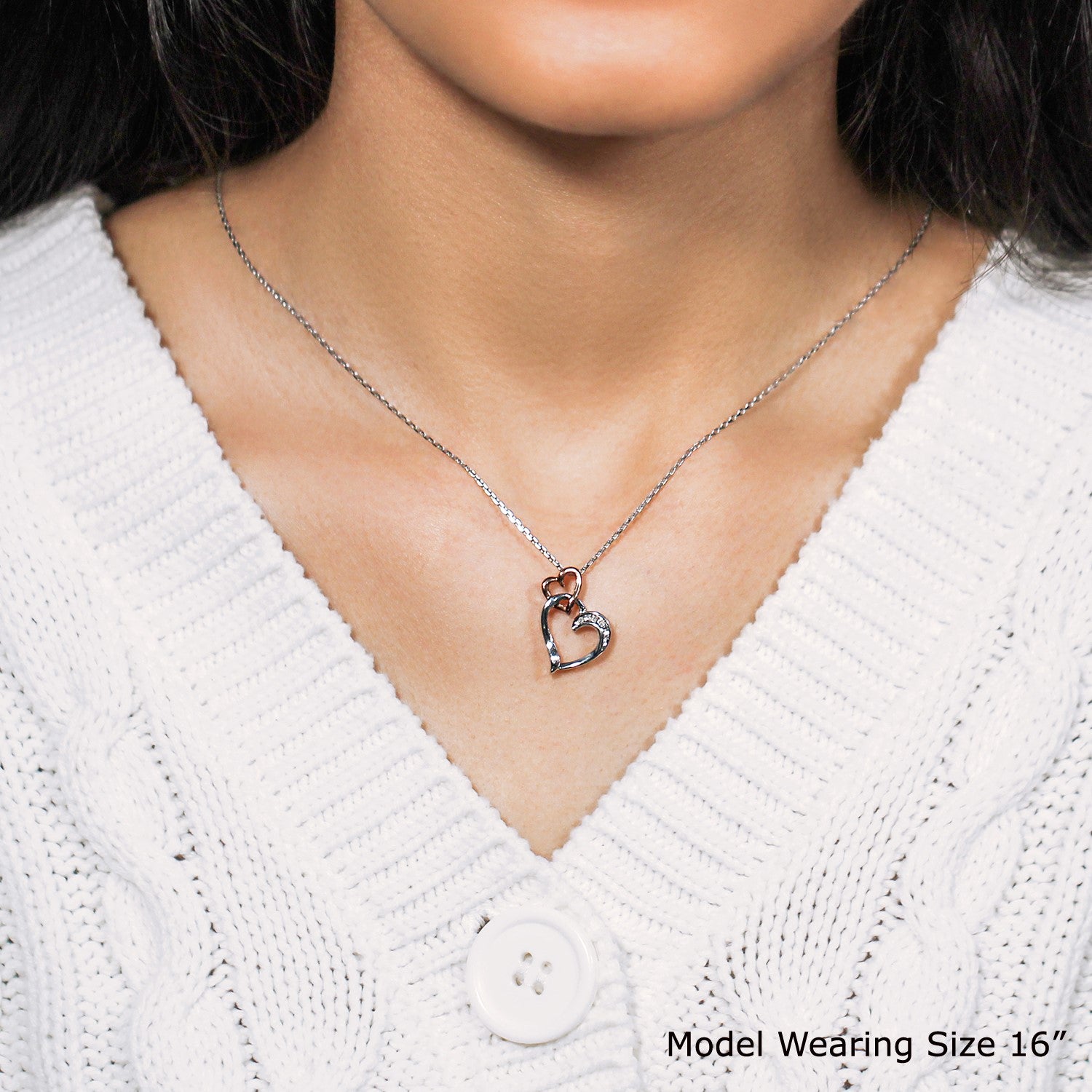 Sterling silver dual heart diamond pendant on a model wearing a white sweater.