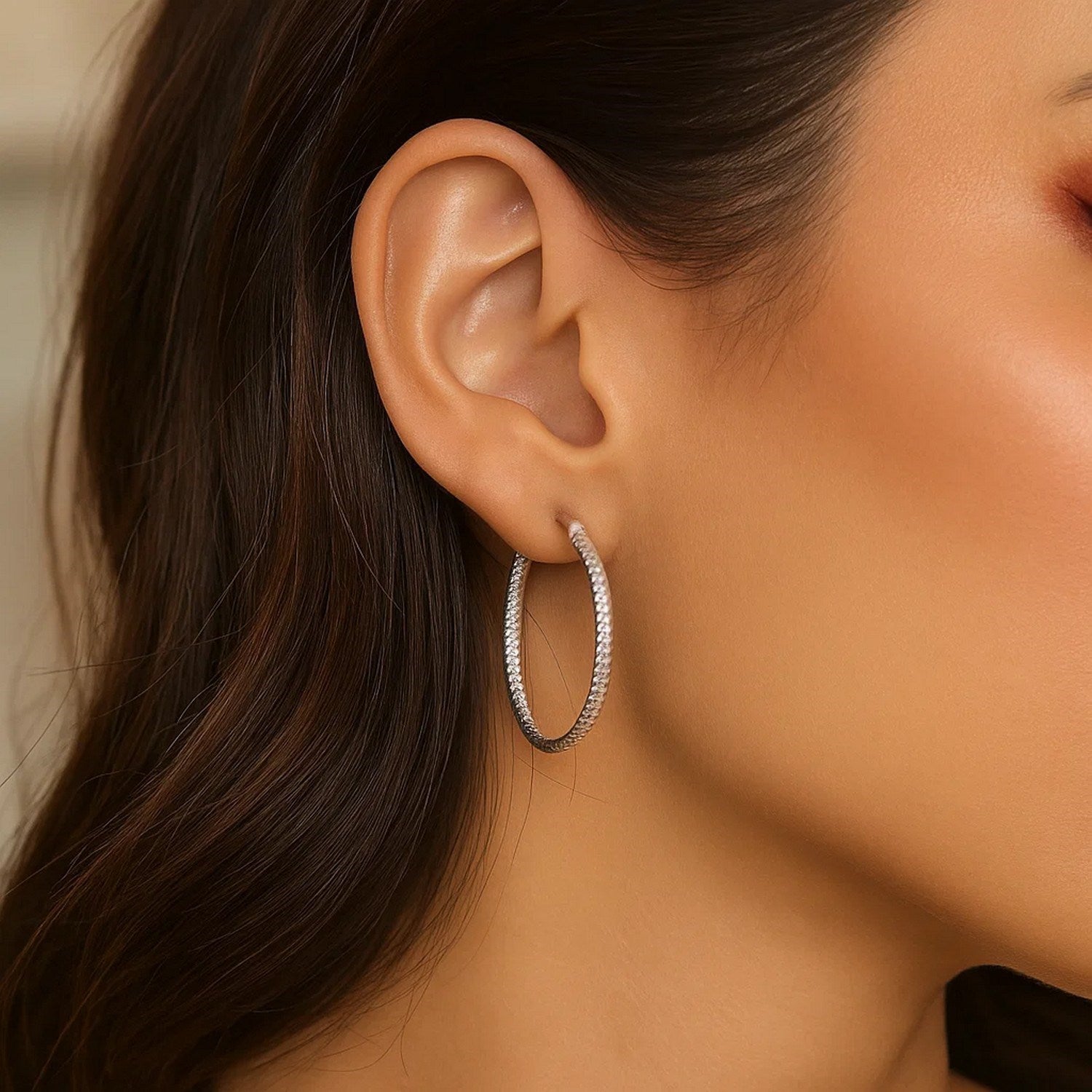 Sterling silver rhodium plated woven style polished hoop earrings on a woman's ear.