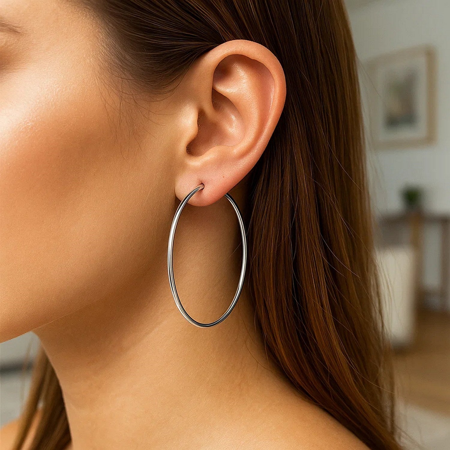 Large polished sterling silver round hoop earring on a woman's ear.