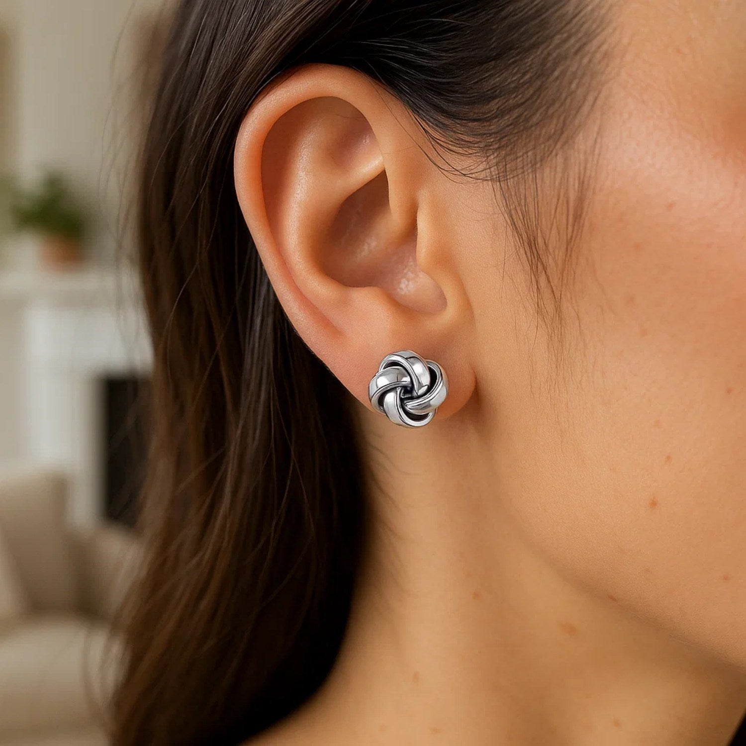 Sterling silver polished love knot stud earring on a woman's ear.