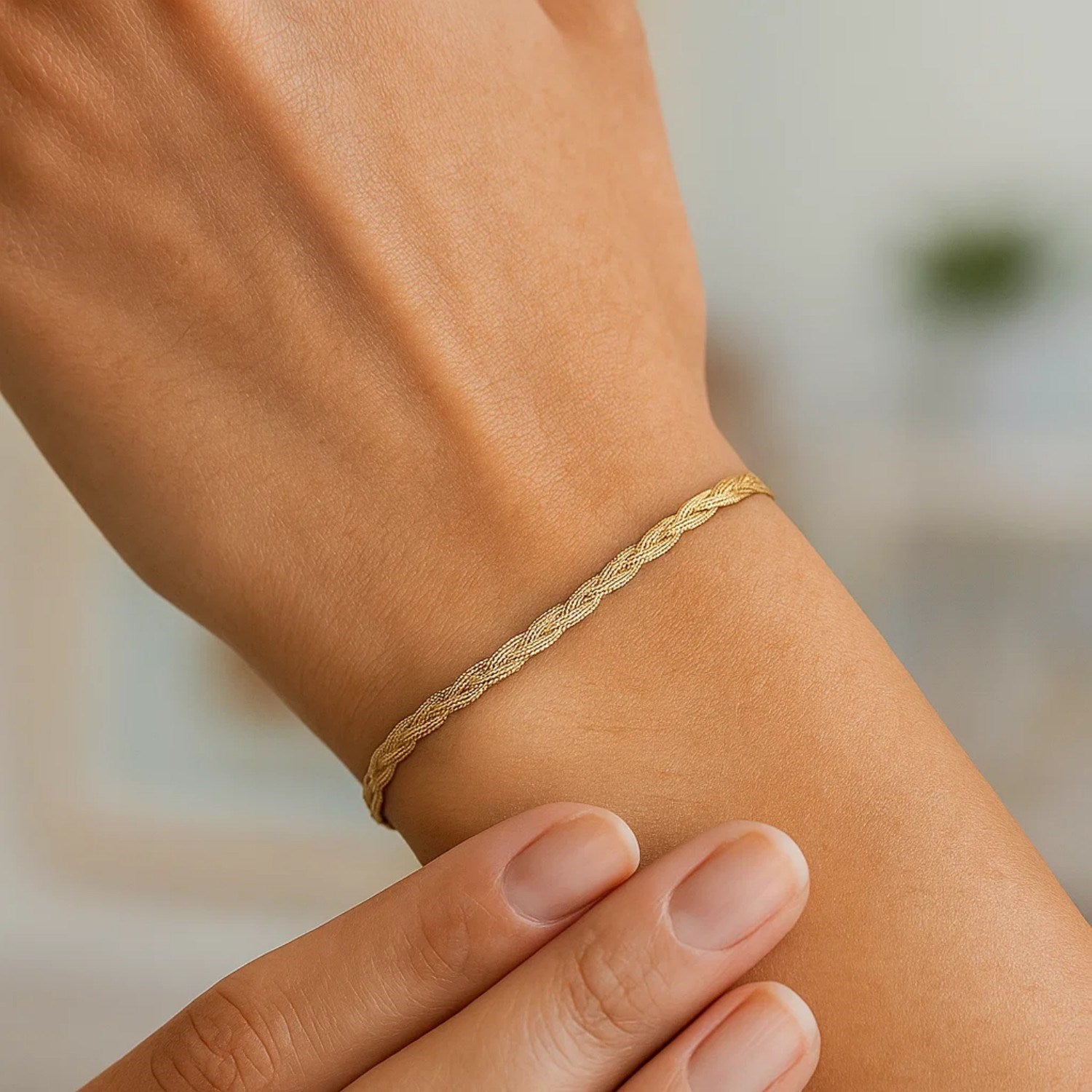 14k yellow gold braided herringbone bracelet on a person's wrist.