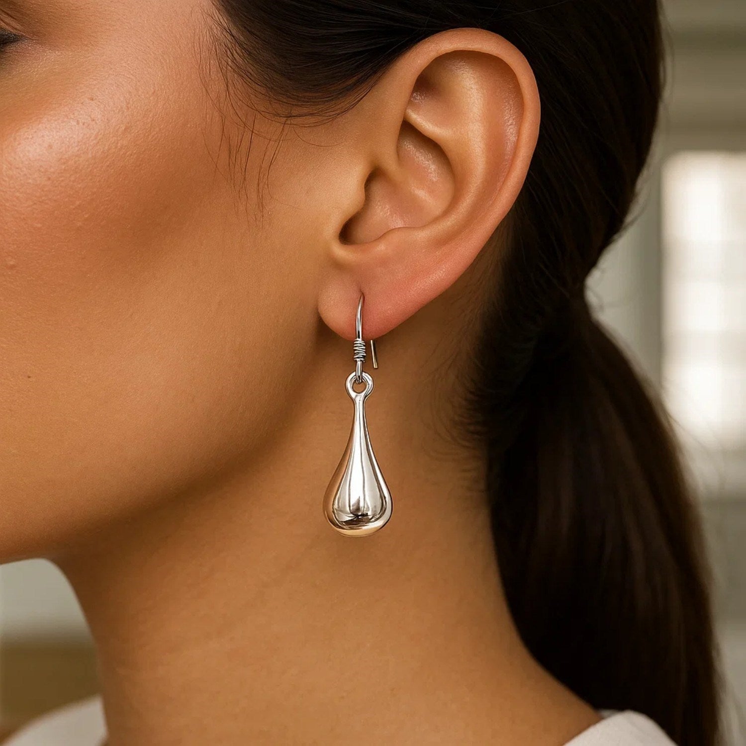Sterling silver long teardrop shape puff drop earrings on a model.