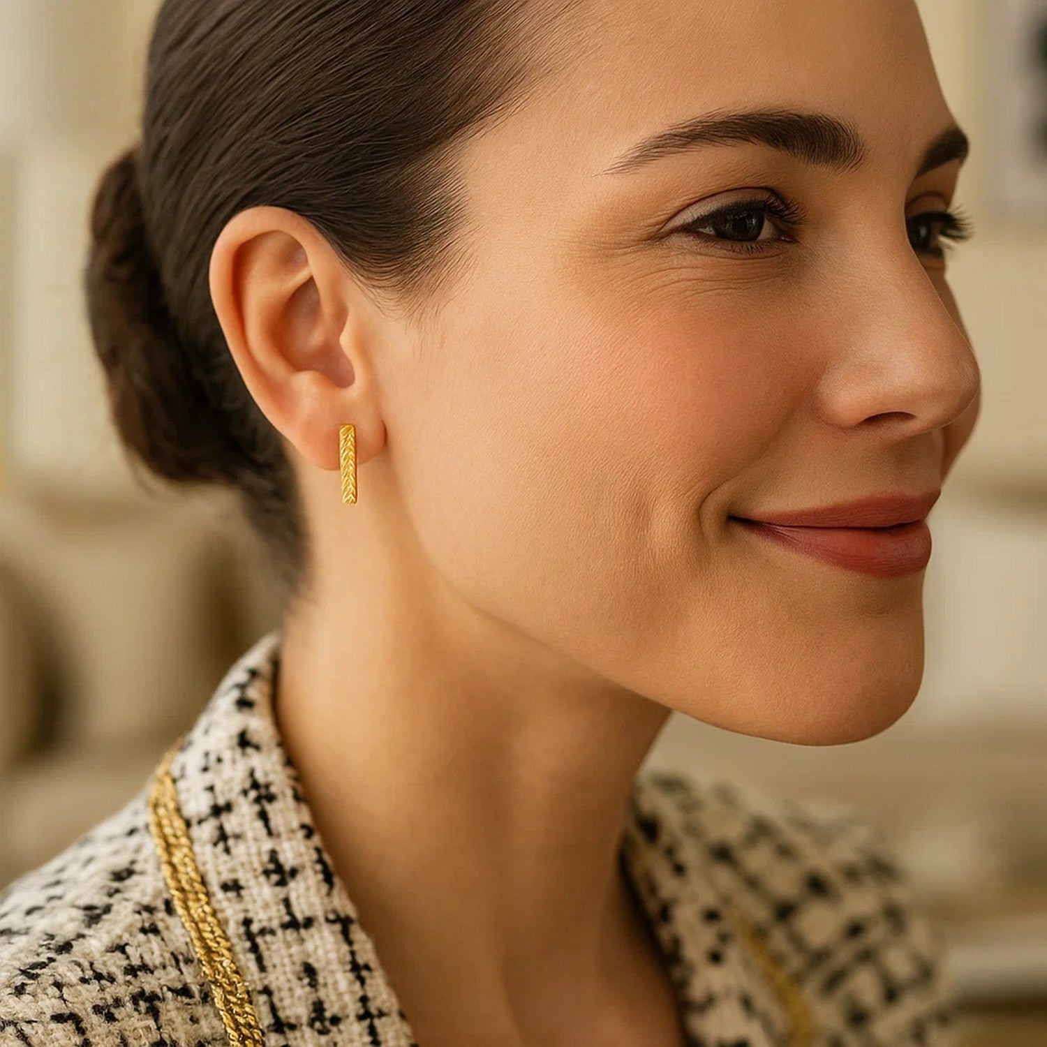 14k yellow gold textured bar earrings are worn by a woman with her hair pulled back.