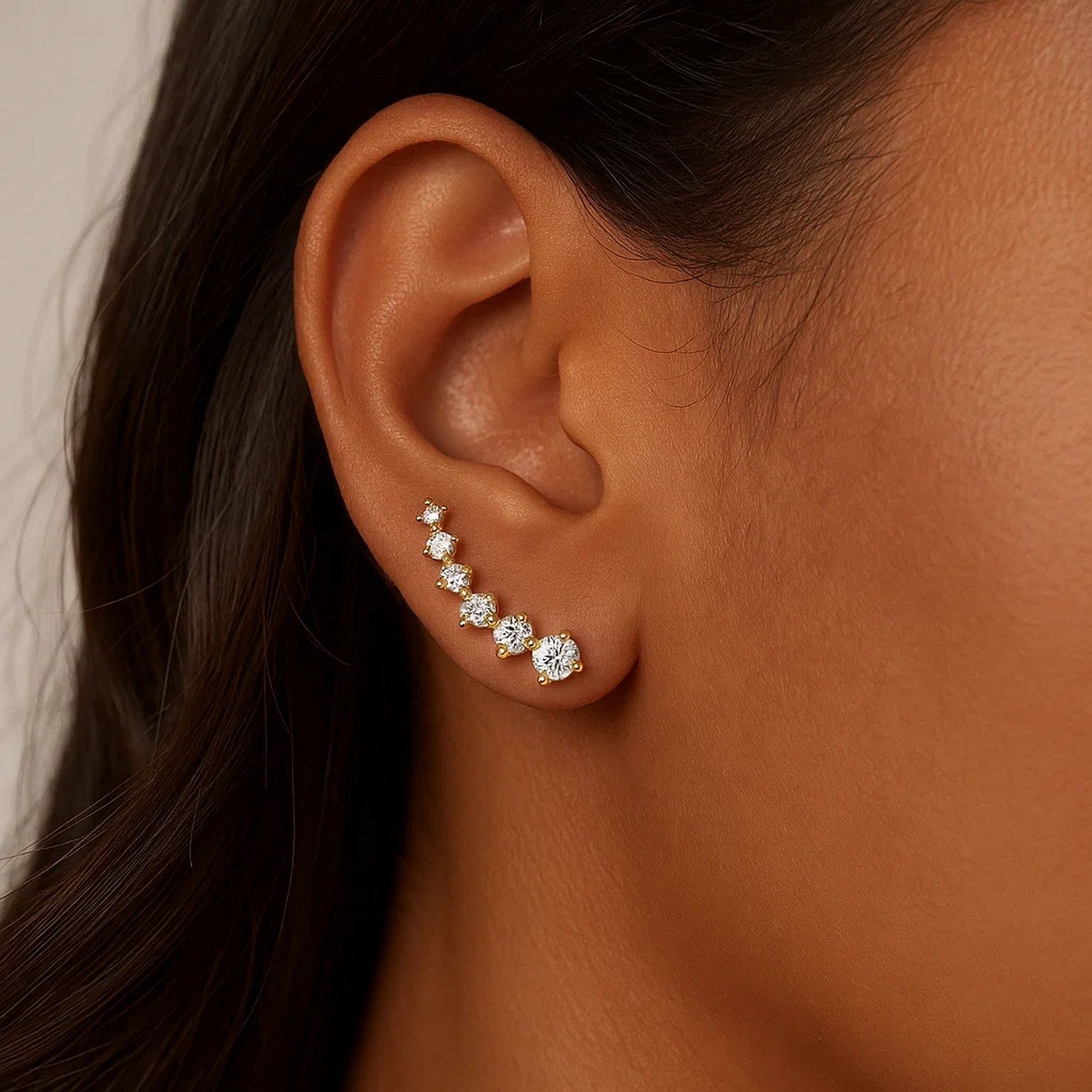 14k yellow gold climber post earrings with seven round cubic zirconias on a woman's ear.