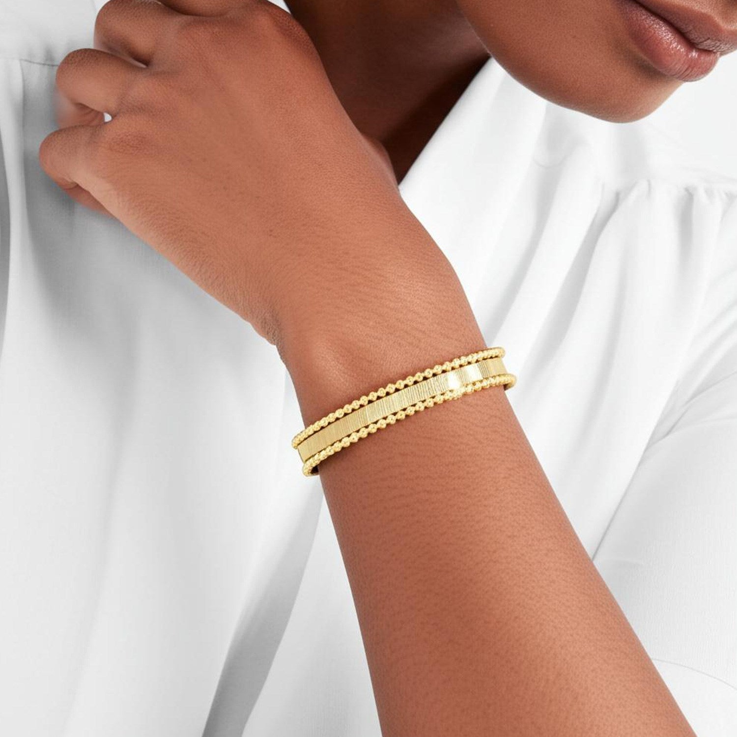 A 14K yellow gold smooth surface pallina cuff bangle on a person's arm.