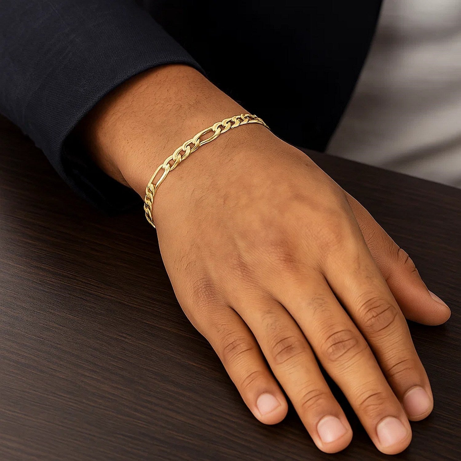A 10k yellow gold Figaro link bracelet on a person's wrist.