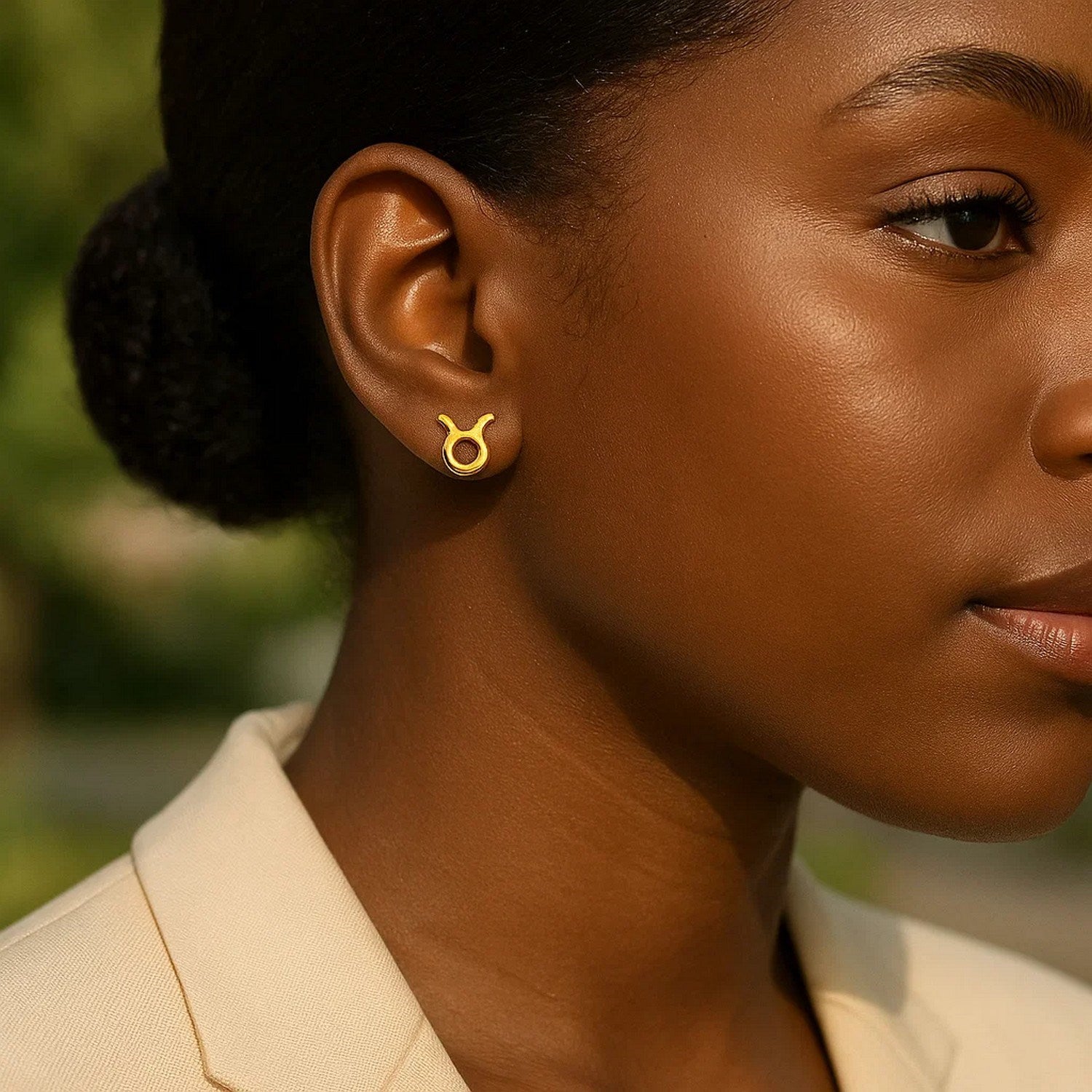 14K yellow gold Taurus stud earrings on a person's ear.
