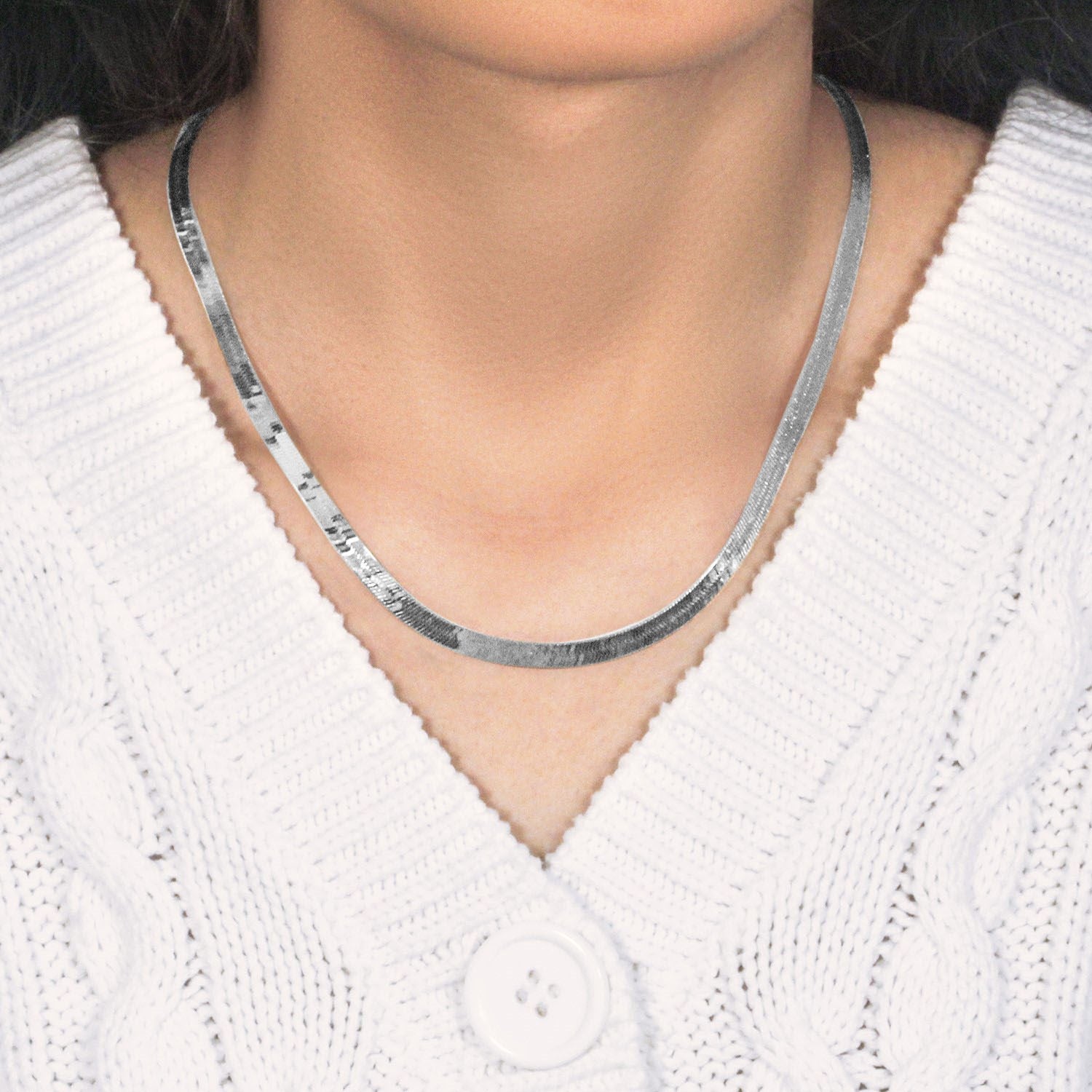 A 14k white gold super flex herringbone chain on a person wearing a white sweater.