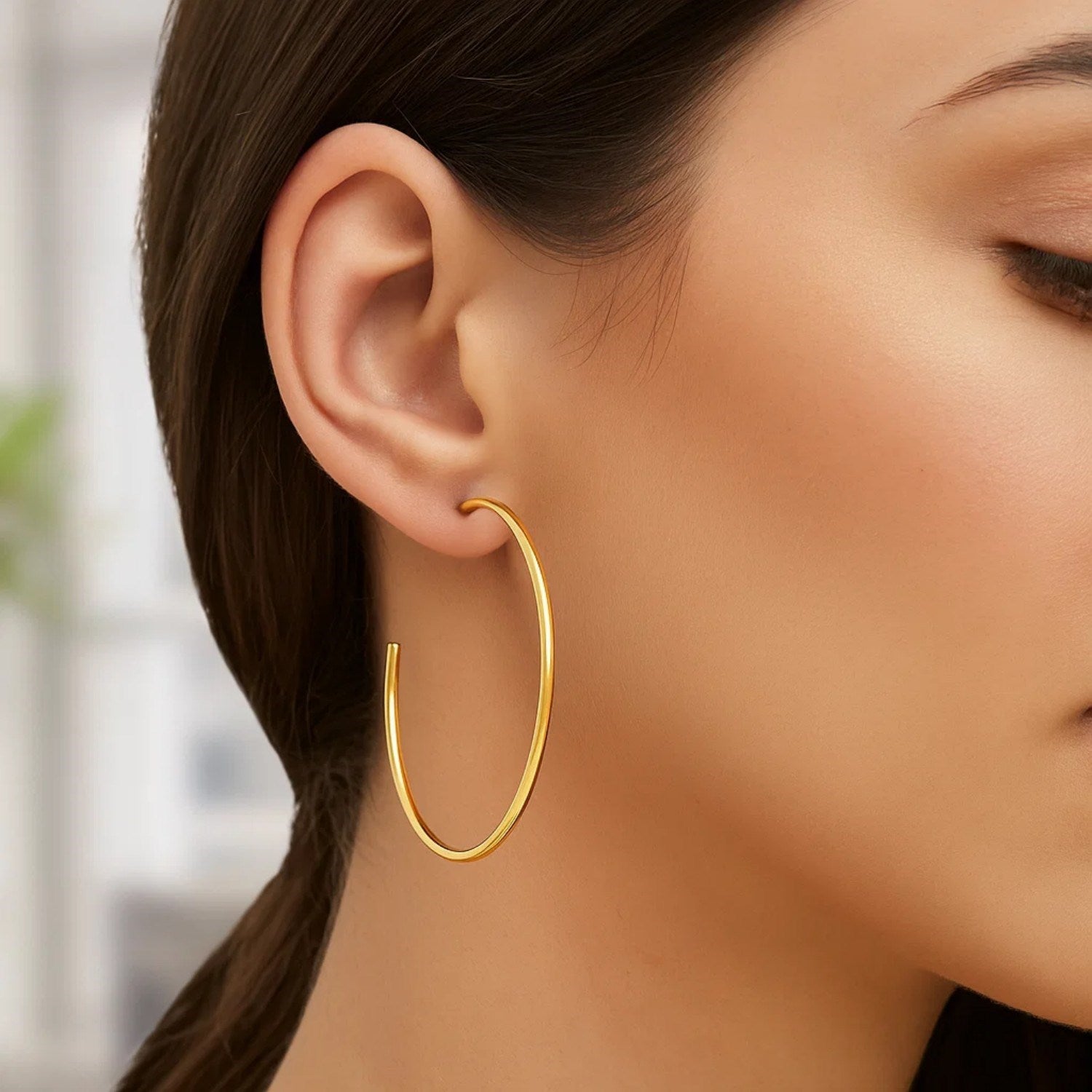 14k yellow gold polished hoop earring on a woman's ear.