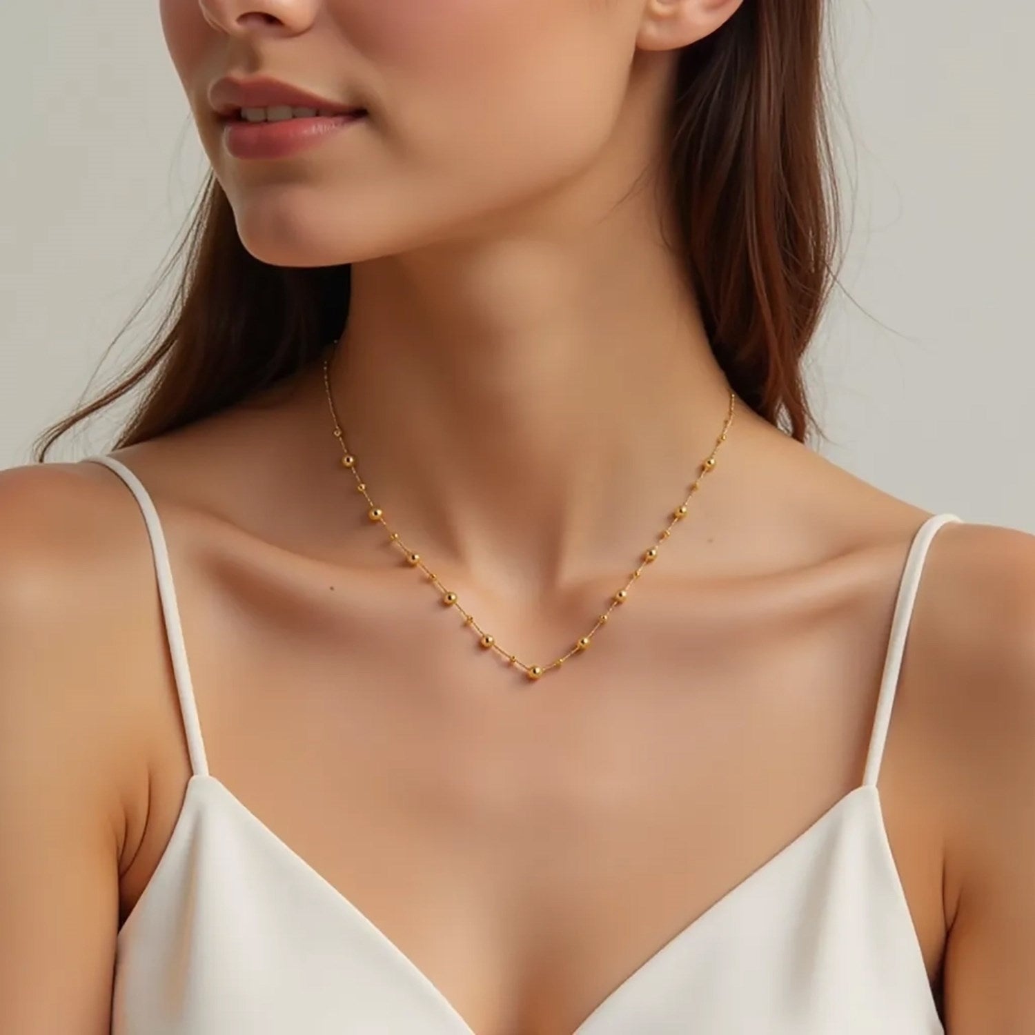 14k yellow gold bead necklace on a woman's neck.