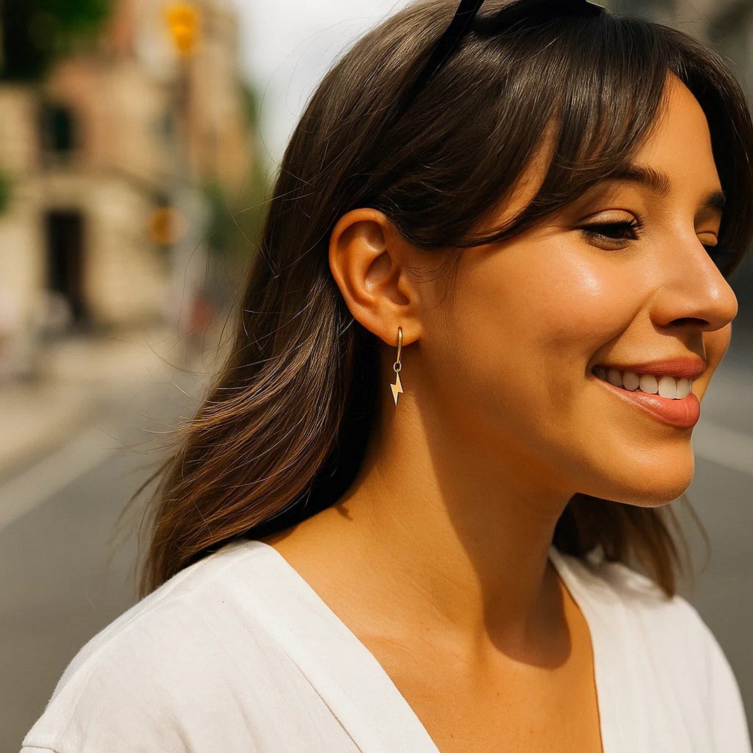 14K yellow gold lightning bolt drop hoop earrings on a smiling woman.