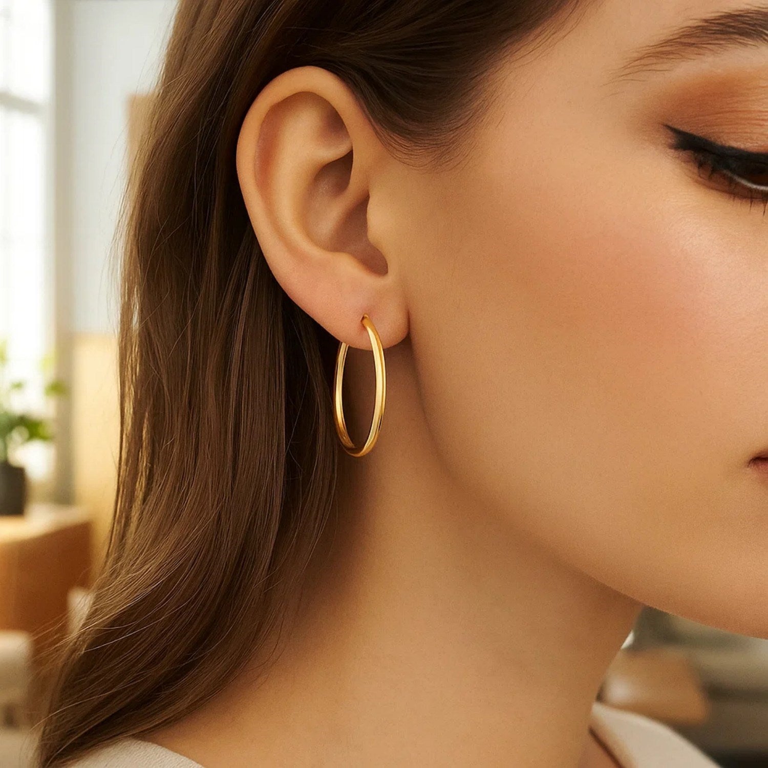 10k yellow gold polished hoop earrings on a woman's ear.