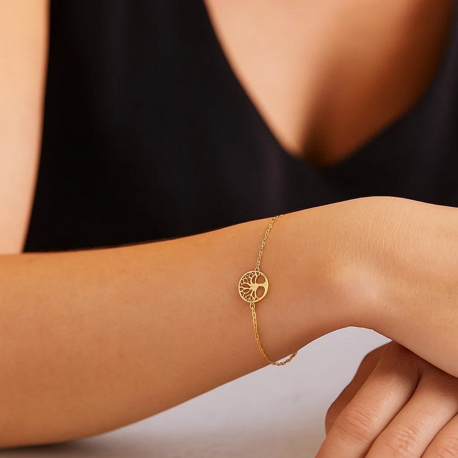 A 14K yellow gold Tree of Life bracelet on a person's wrist.