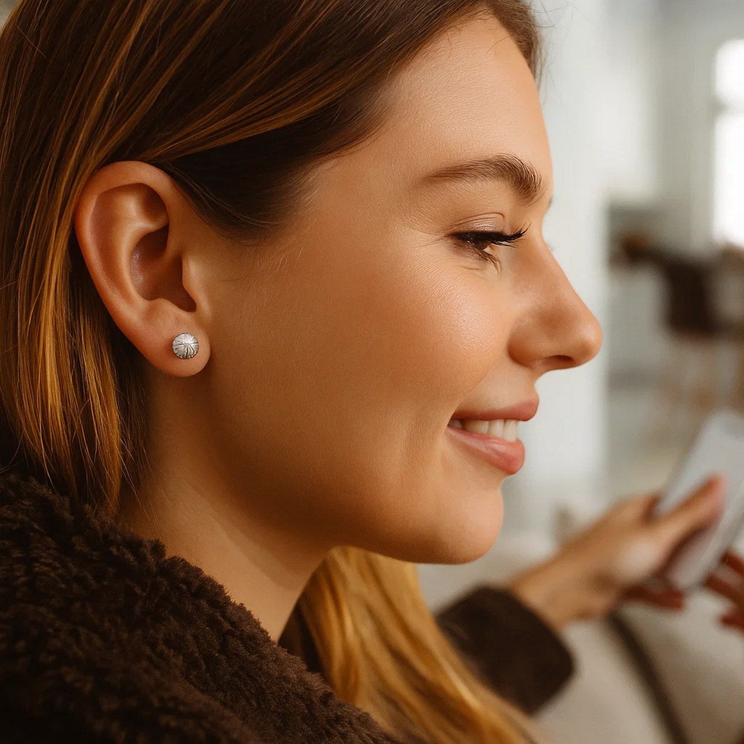 14K white gold ball earrings with linear texture on a woman's ear.